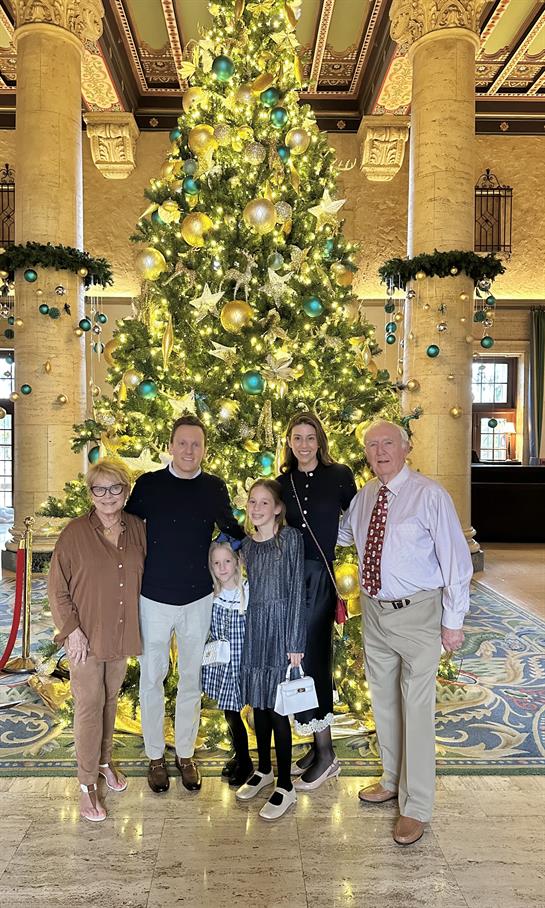 A group of people posing for a photo in front of a christmas tree