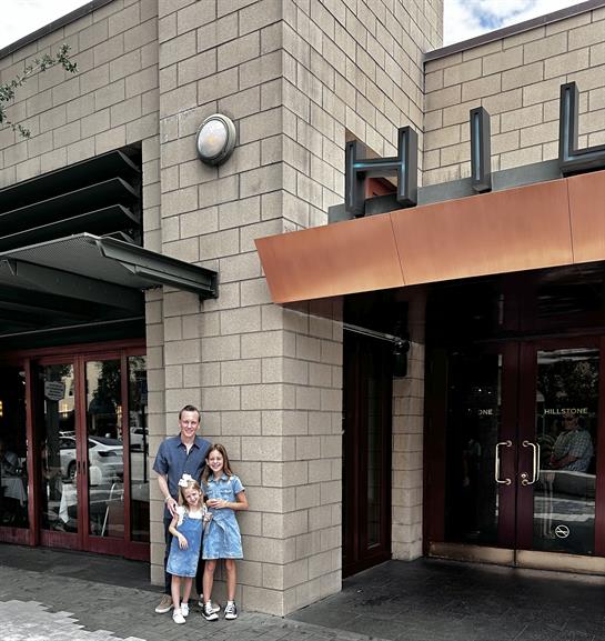 A man and two children standing in front of a building