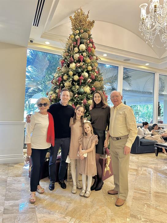 A group of people posing for a photo in front of a christmas tree