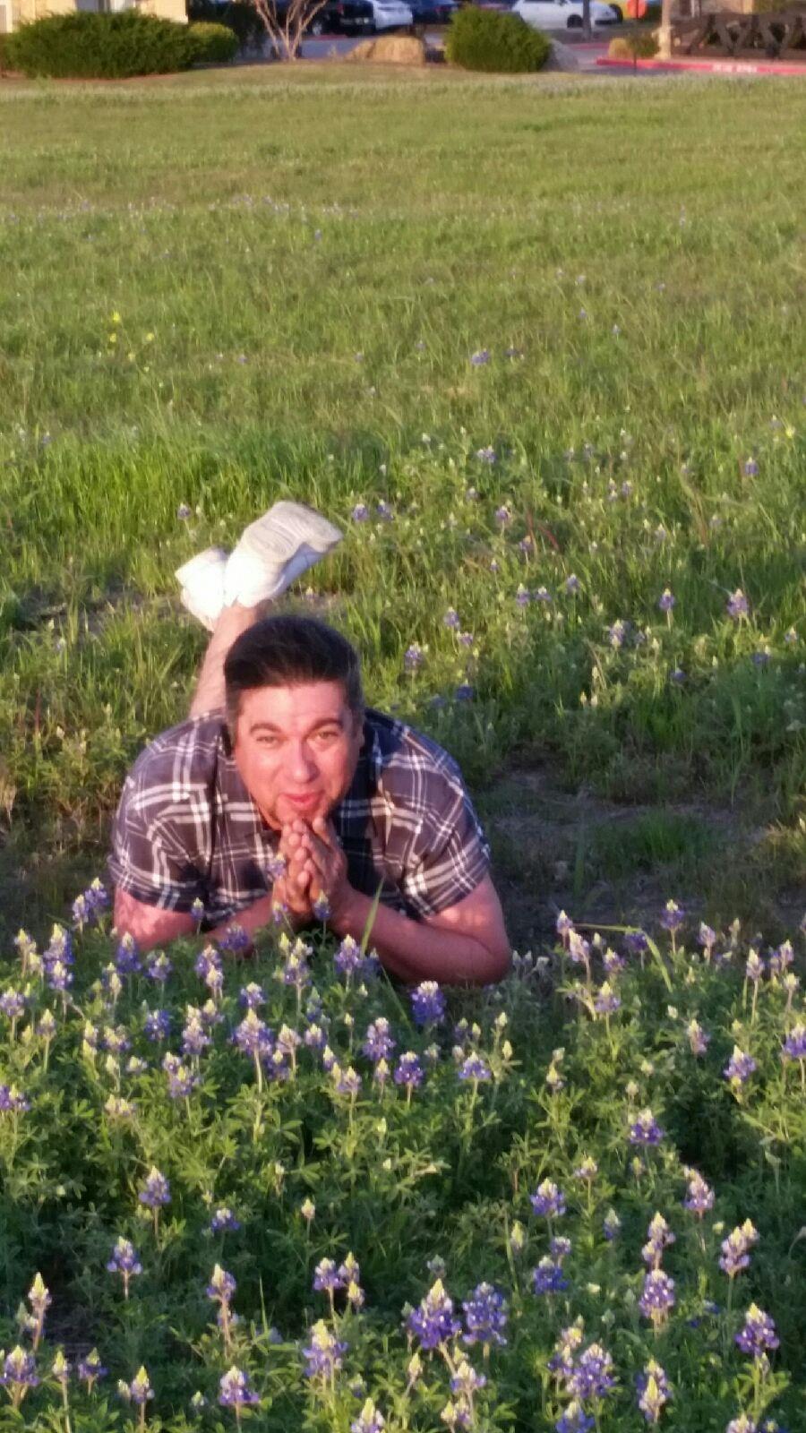 A person enjoys lying down among wildflowers as the sun sets in a Texas field.