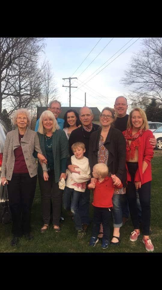 A large family celebrates their reunion outdoors among blooming trees and sunshine.