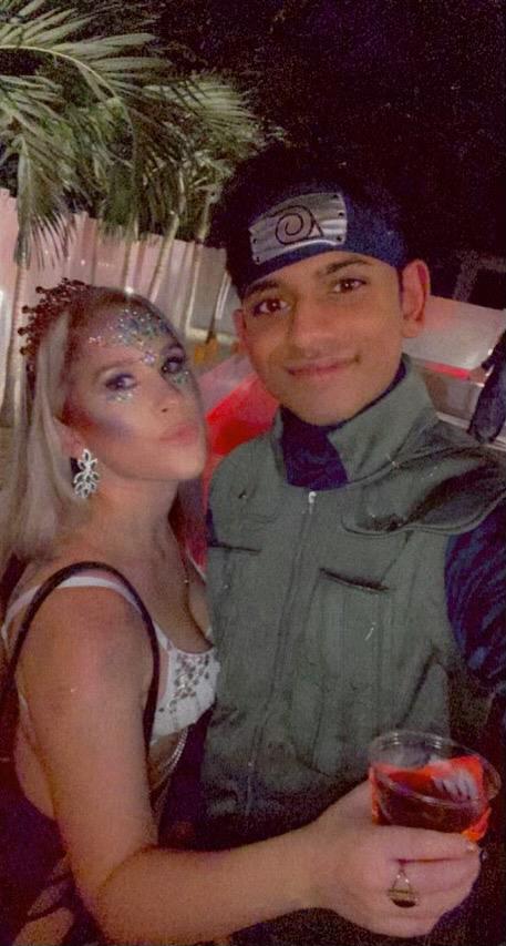 Two people pose at a lively party, sporting elaborate costumes and joyful smiles.