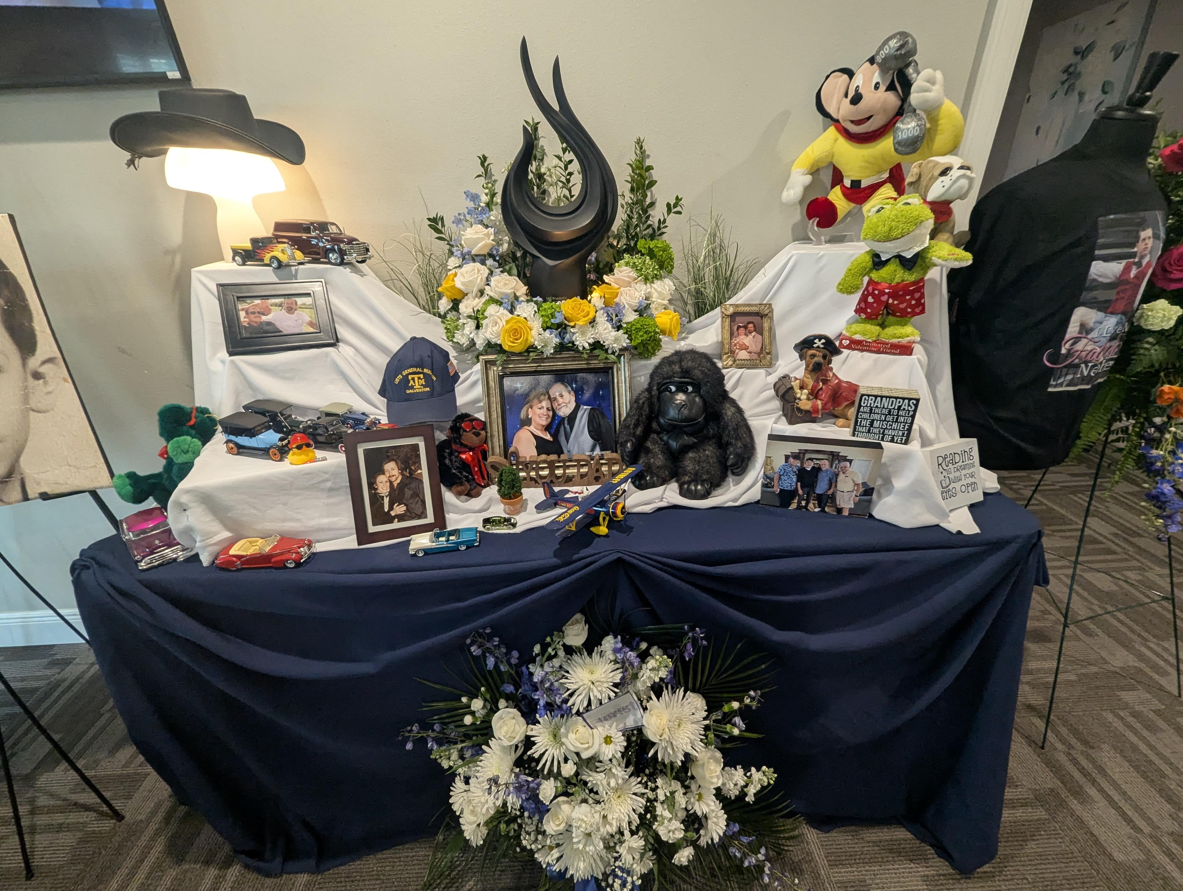 A flower-decorated table honors a beloved person, showcasing their life and interests.