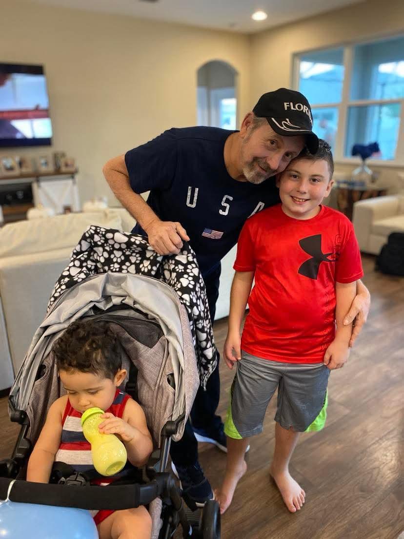 Two cheerful boys pose with a man in a comfortable indoor setting, enjoying their time together.