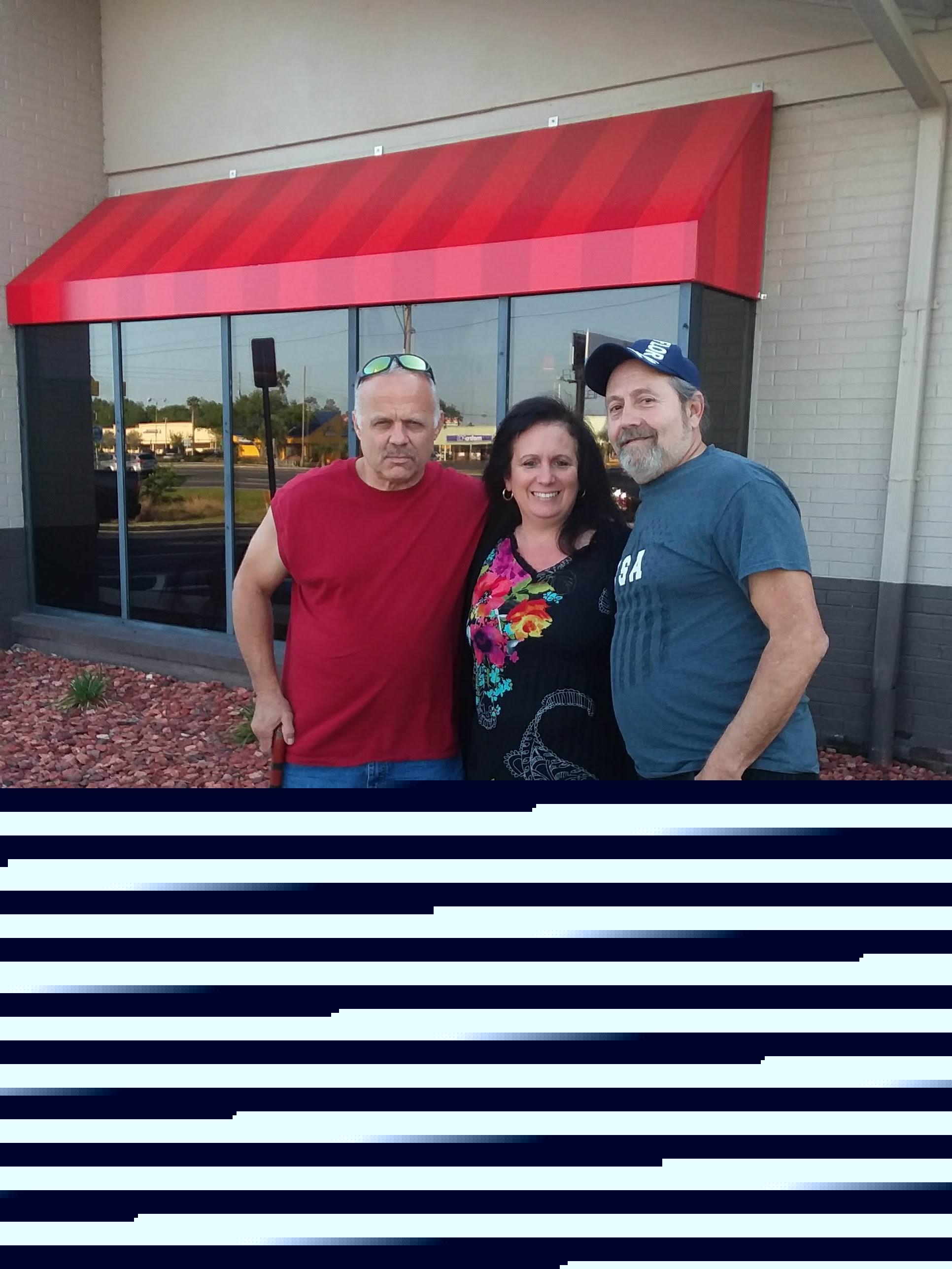 Three friends pose outside a restaurant, highlighting their camaraderie and relaxed vibe.