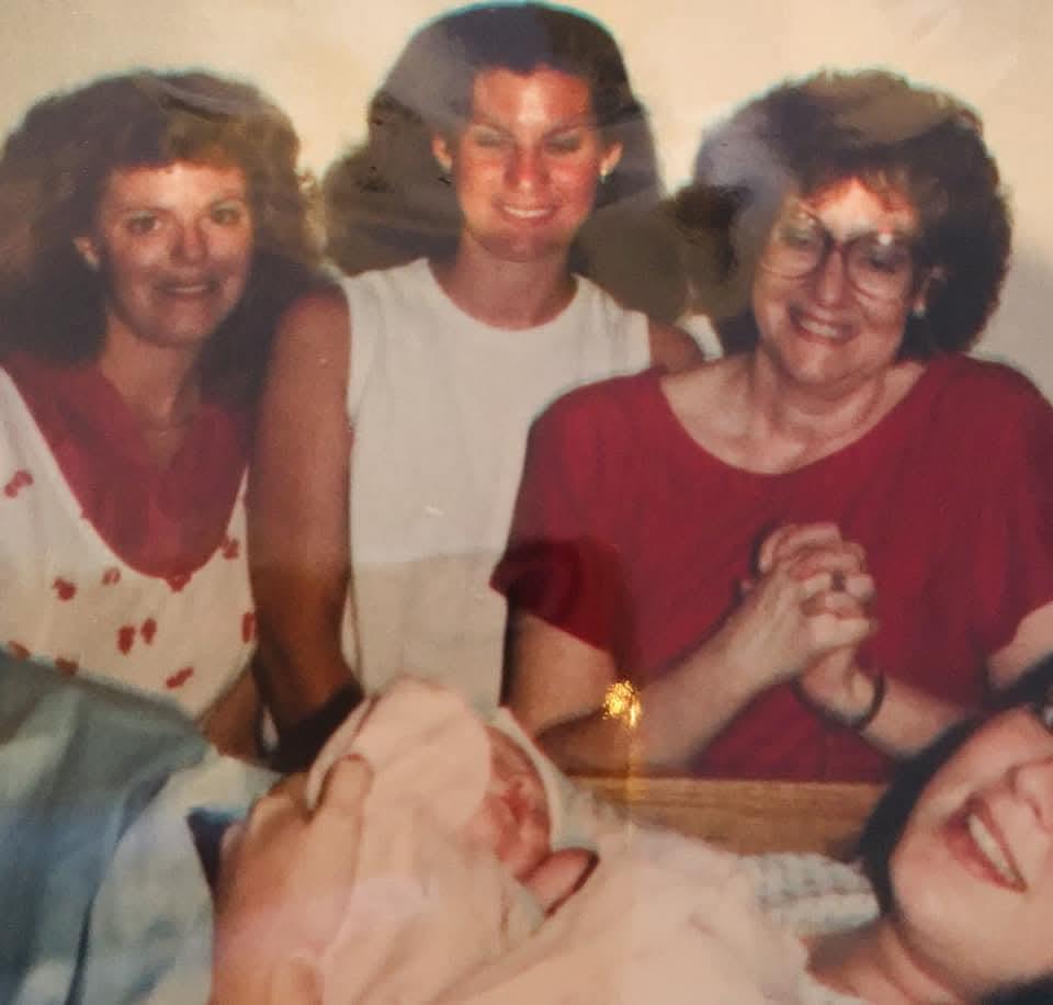 Four family members share smiles and laughter in a cozy indoor moment.