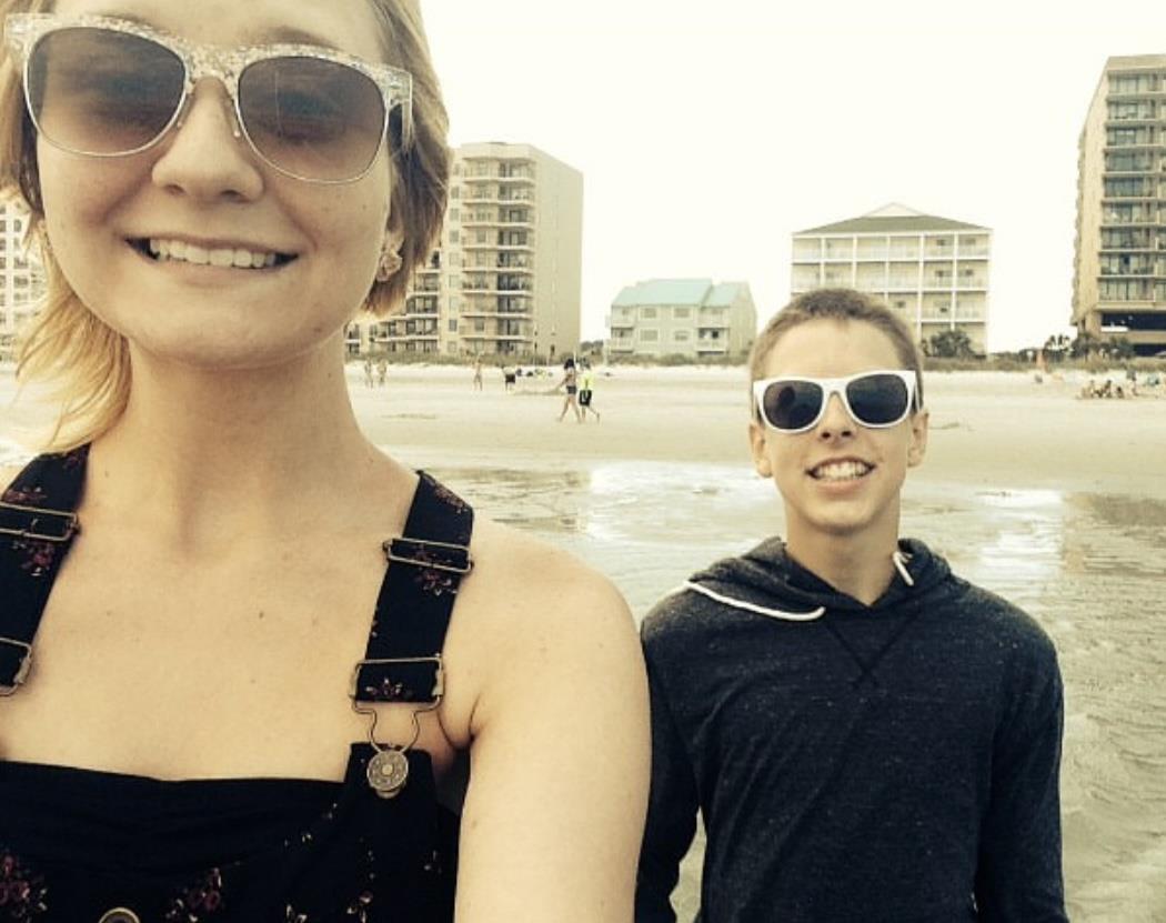 Friends take a joyful walk along the beach, enjoying the sunny weather and each other's company.