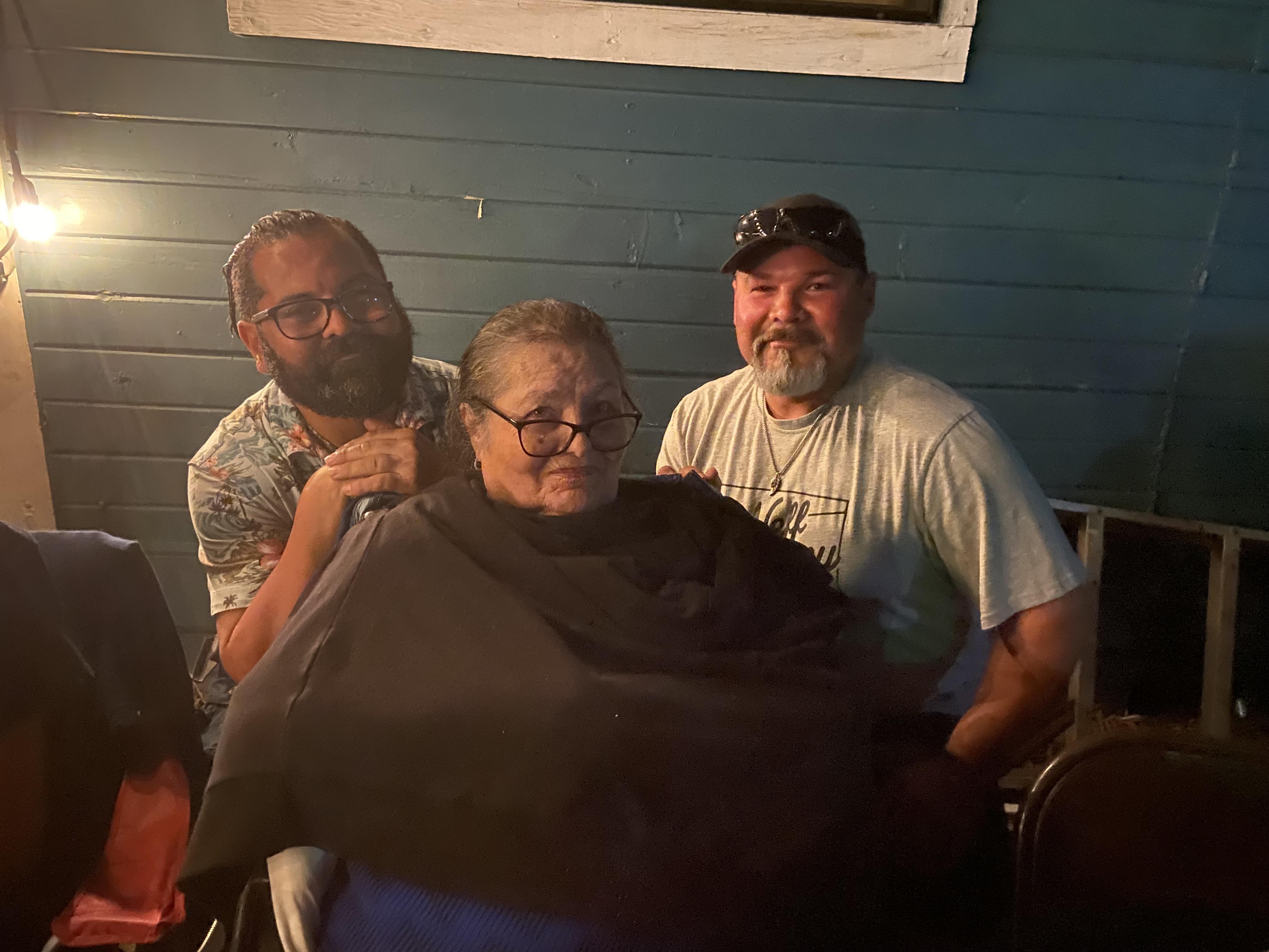 Three men gather closely to enjoy each other's company in an outdoor setting at night.