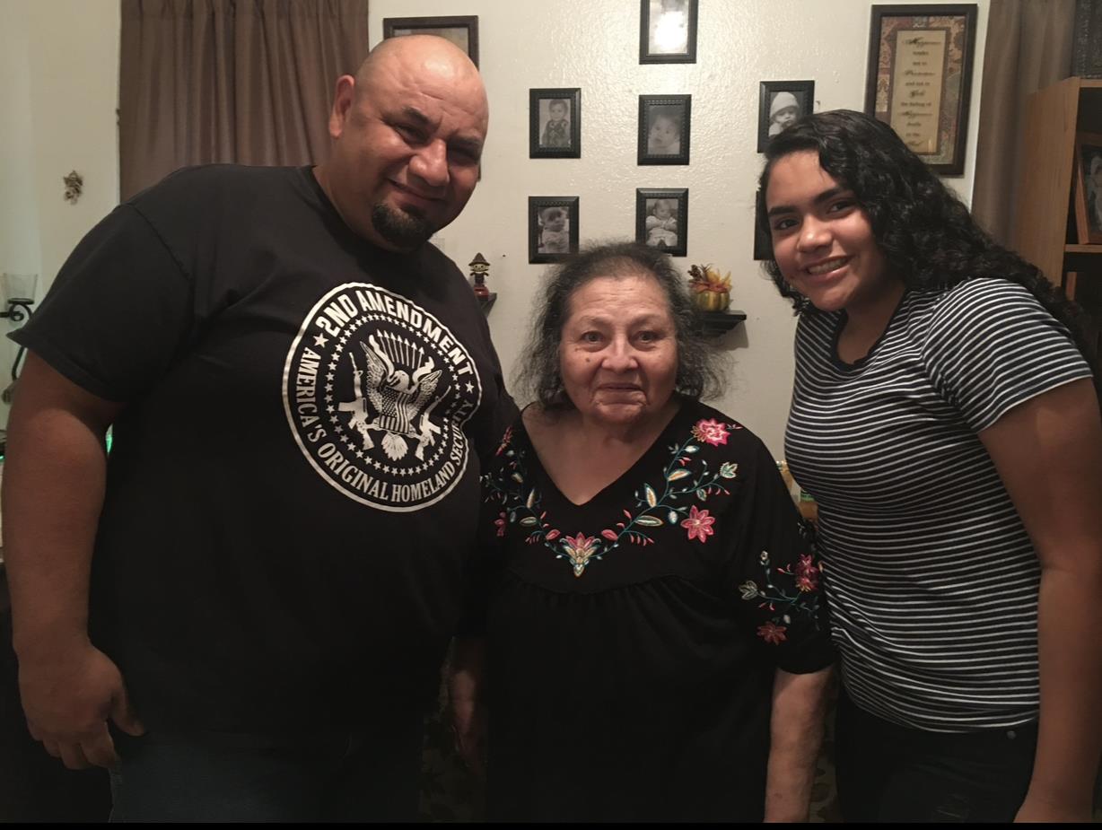 Three family members share a joyful moment in a cozy living room adorned with framed photos.