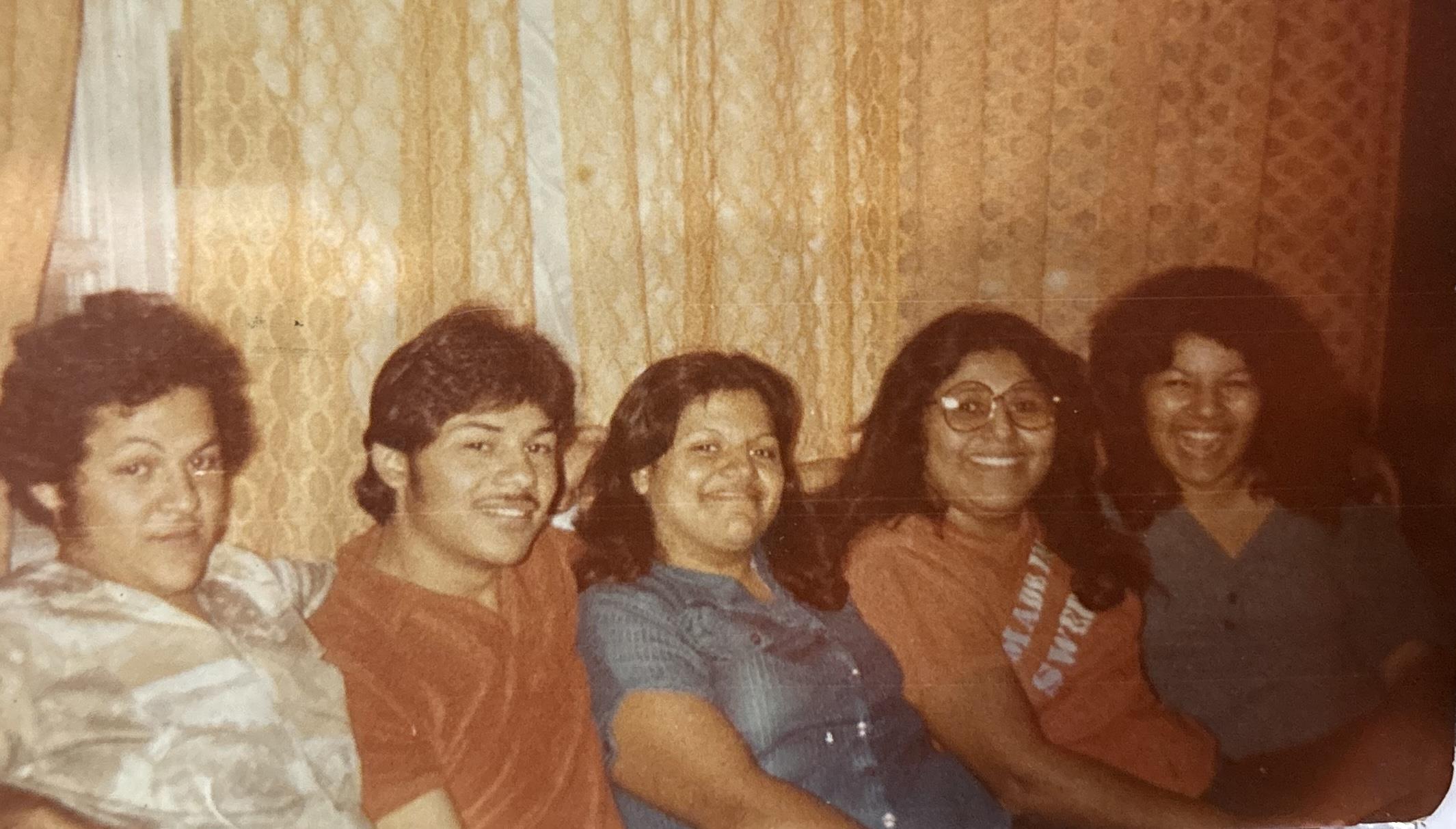 Five friends sit closely together, sharing laughter and stories in a warm, inviting room.