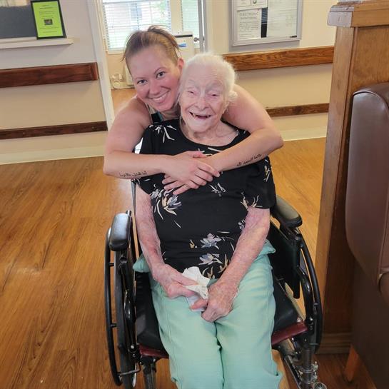 A woman hugging an old woman in a wheelchair