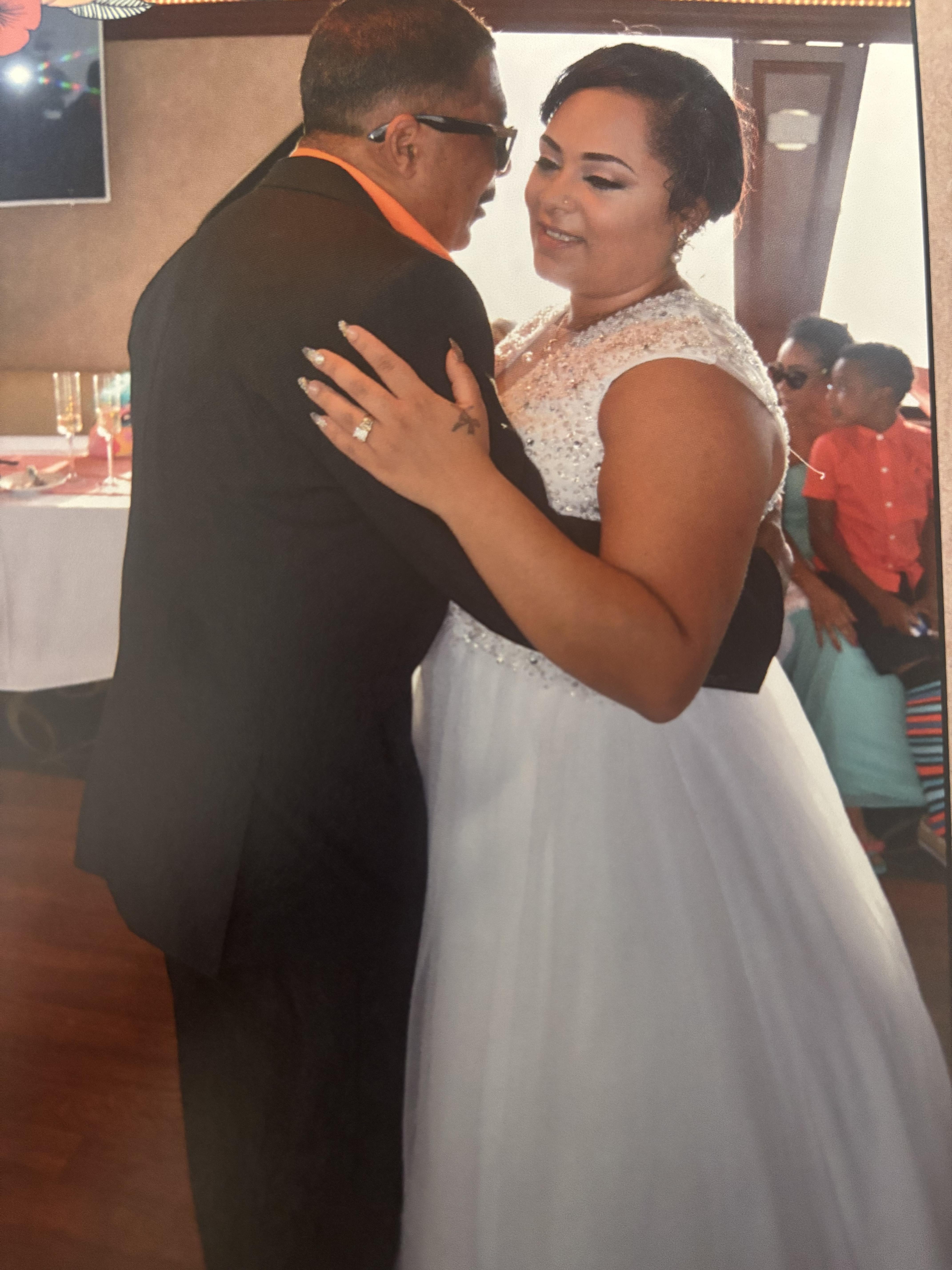 A man and woman dance closely together at a wedding reception, surrounded by joyful guests.