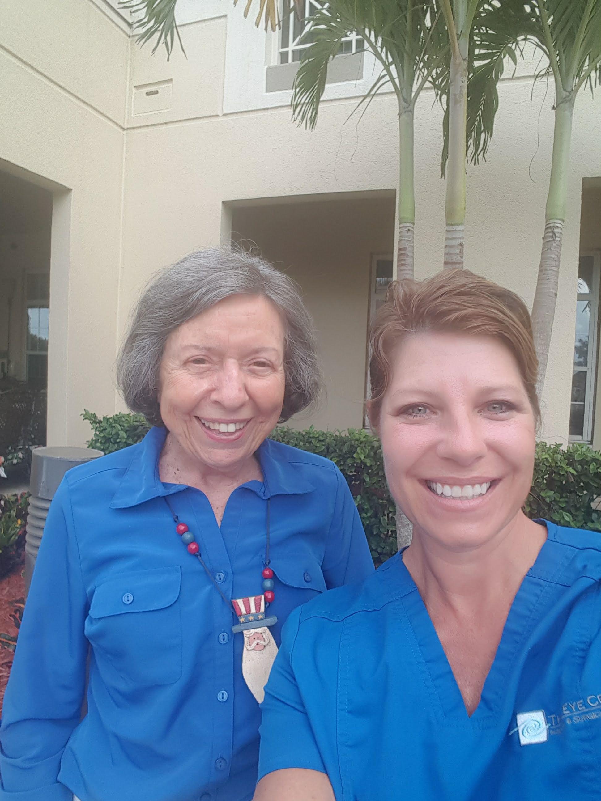 Two women are standing next to each other, smiling and enjoying a sunny day outdoors.