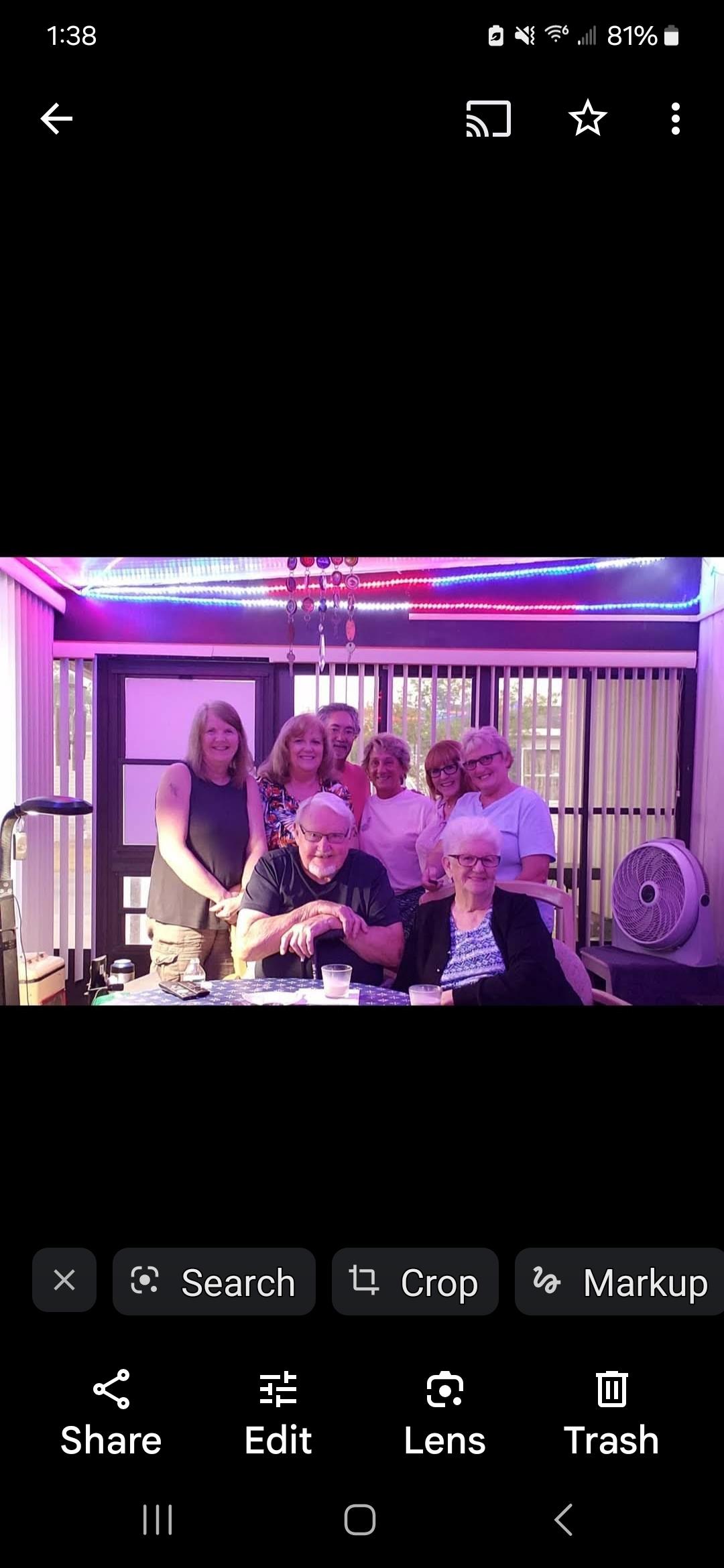 A joyful group of friends and family members gathers in a warmly lit indoor setting, sharing laughs.