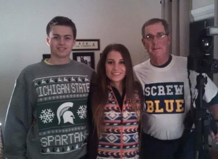 A group of friends wearing festive sweaters enjoy a joyful moment during a holiday gathering.