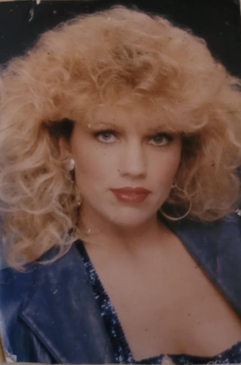 A confident woman flaunts her curls, bold lipstick, and stylish outfit.