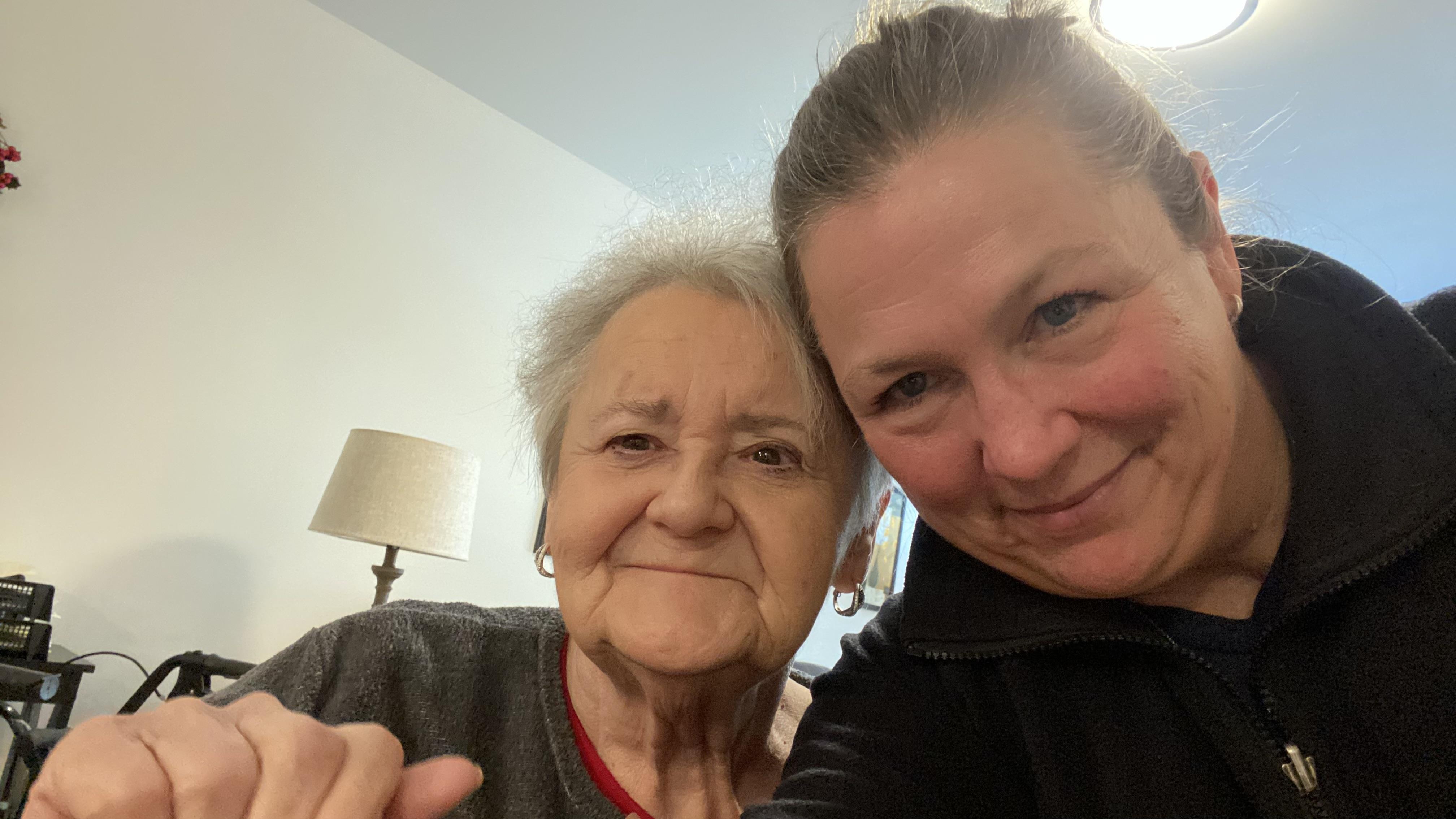 Two women smile happily while posing closely together, enjoying a heartfelt visit.