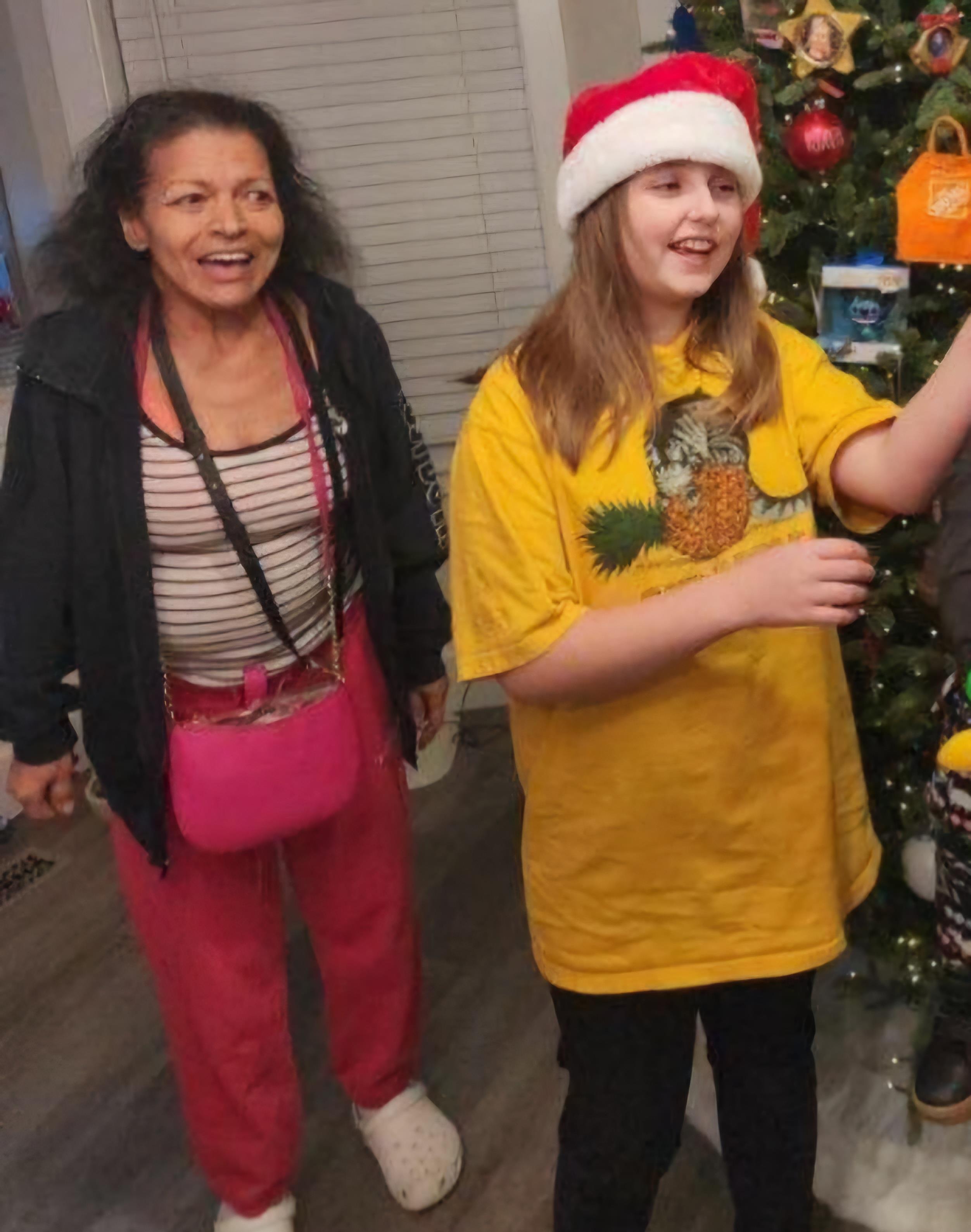 Two family members enjoy a holiday celebration indoors, dressed in festive clothing and smiling.