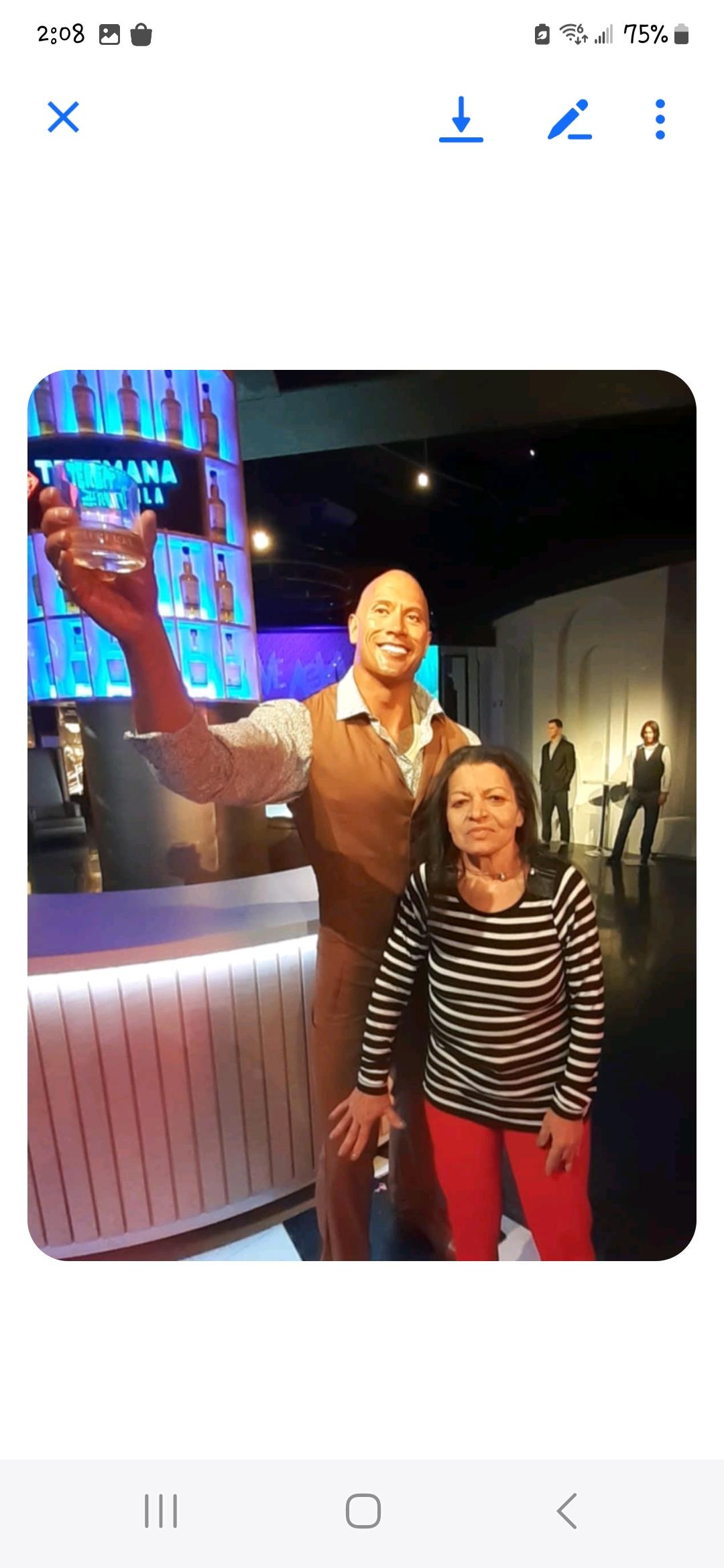Woman enjoys her time at an interactive exhibit, posing with a lifelike figure in a lively setting.