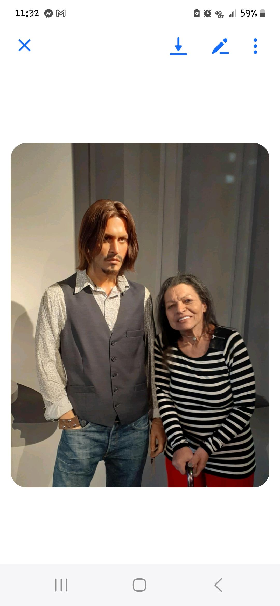 Two wax figures stand together as visitors engage with the exhibit in a lively environment.