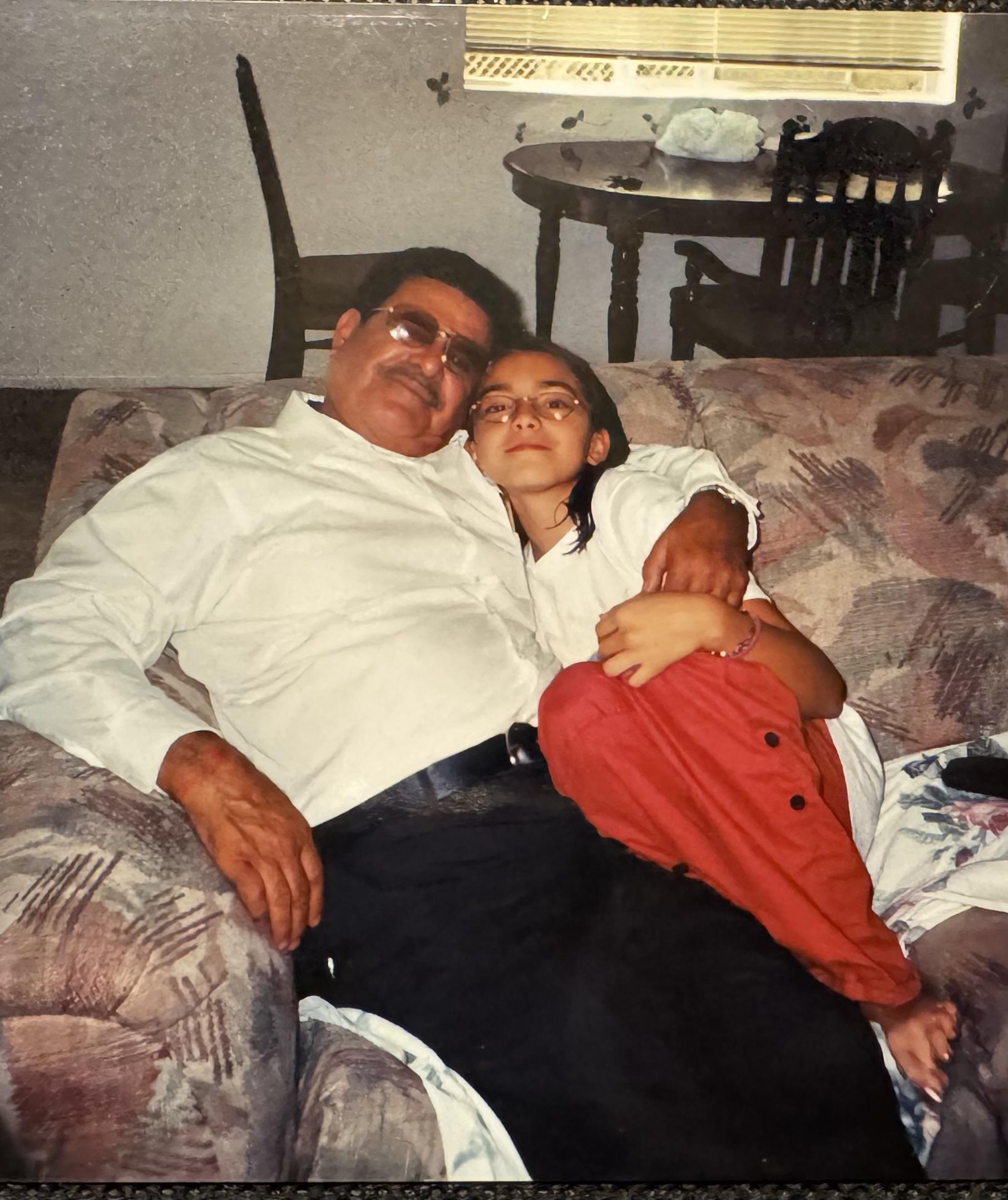 A child affectionately leans against an adult on a couch, capturing a tender family moment at home.
