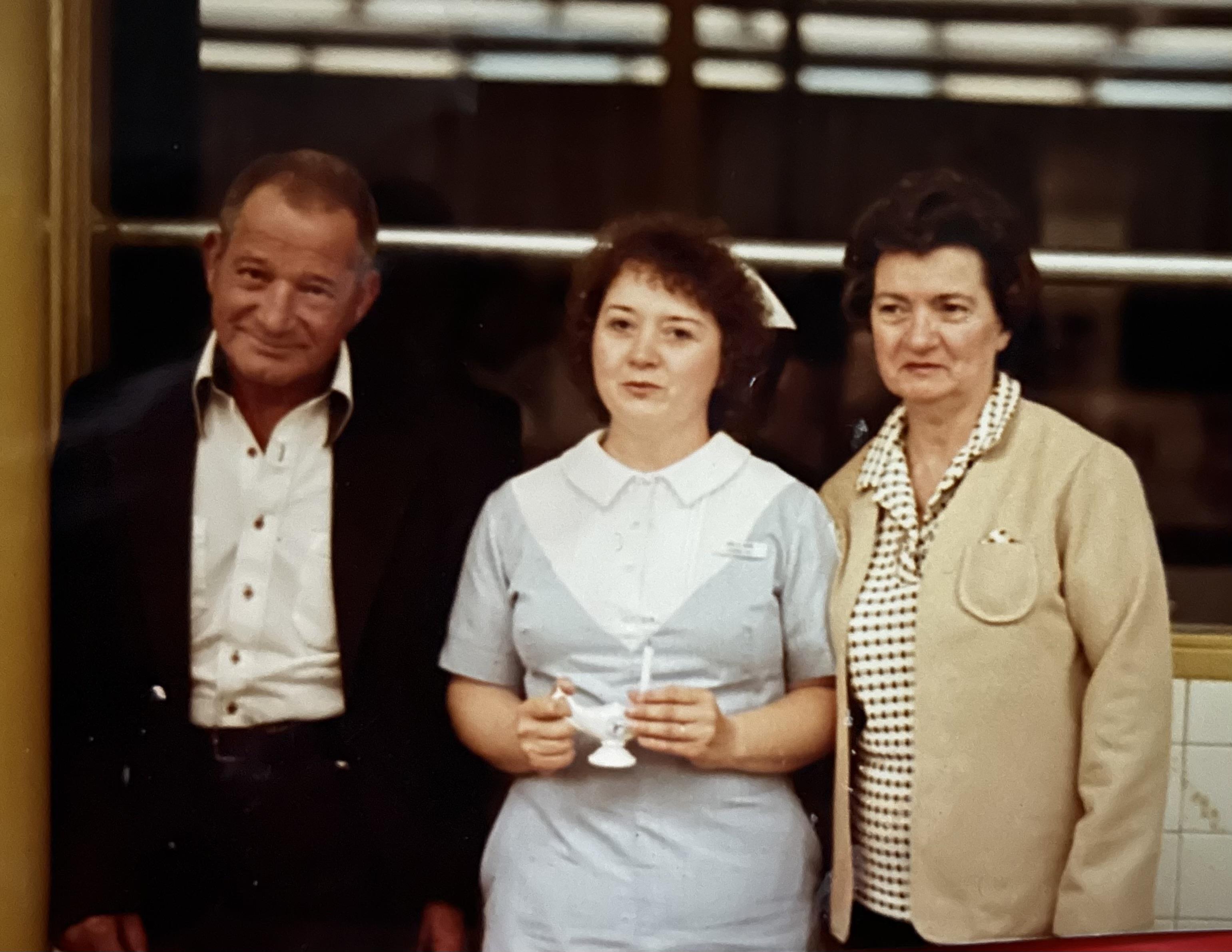 Three people smile while standing beside each other in a medical setting.