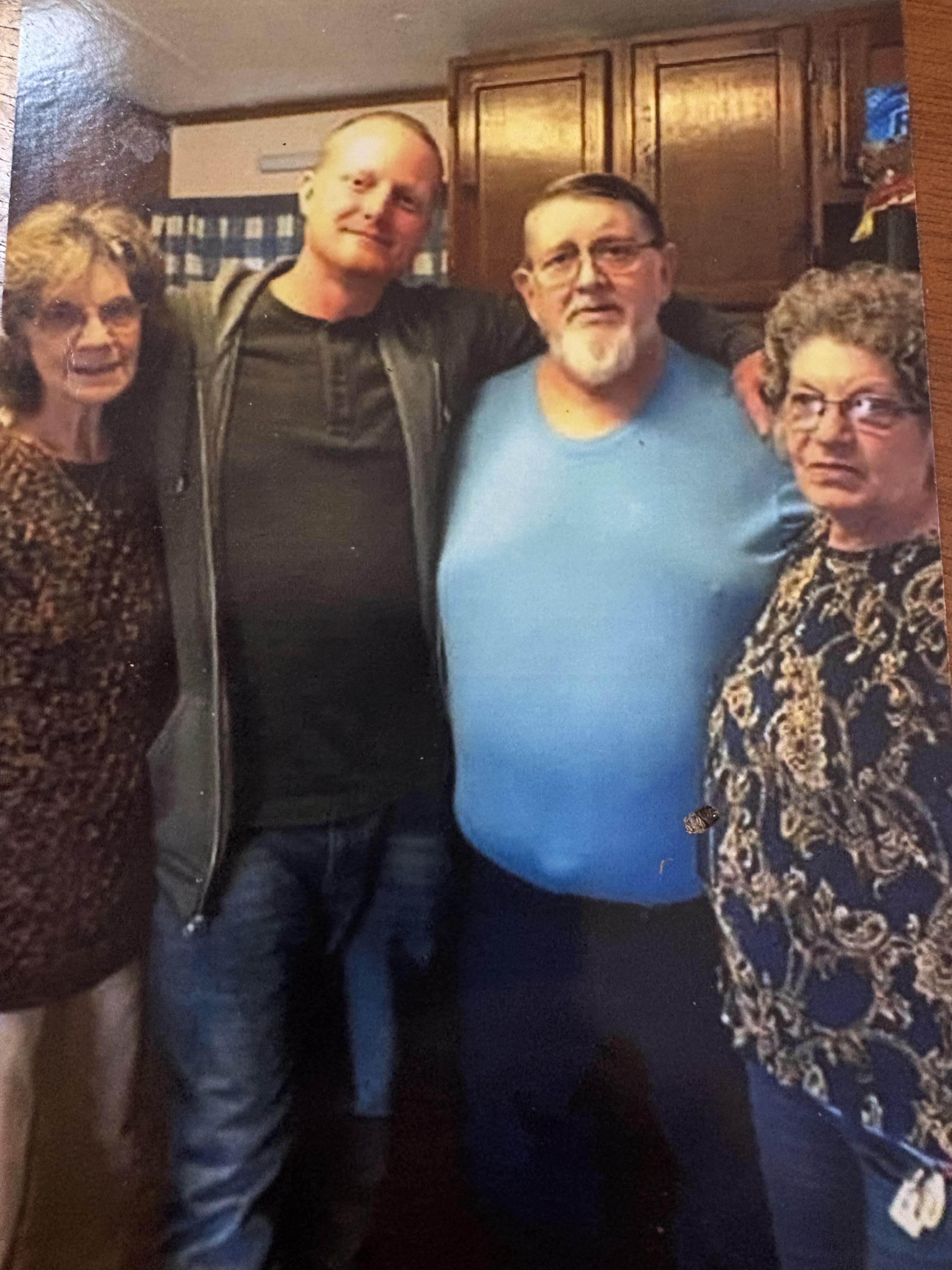 Four relatives stand close together, smiling in a warm kitchen filled with memories and love.