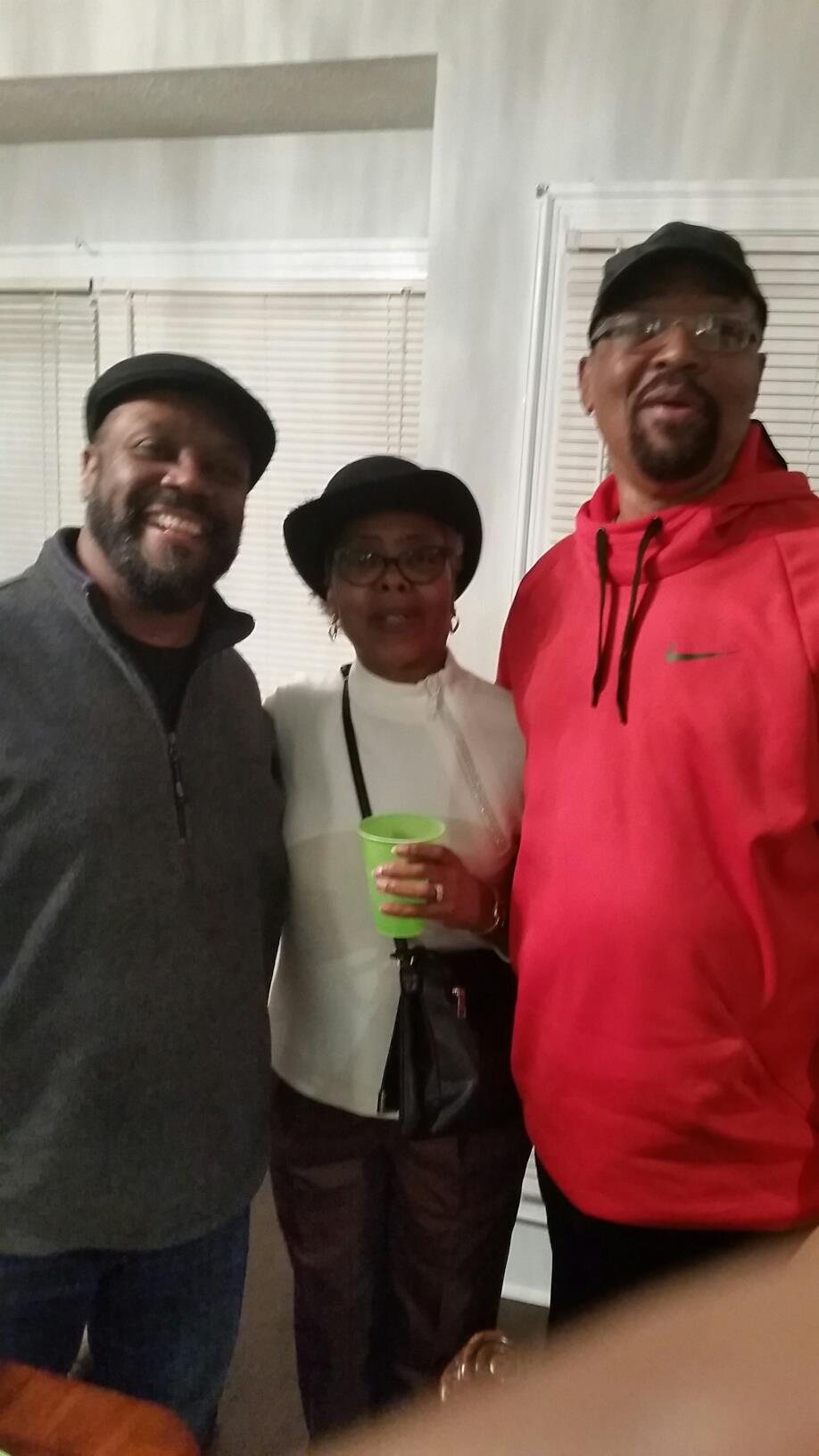 Three friends enjoy a warm moment at a social event in a comfortable indoor space.