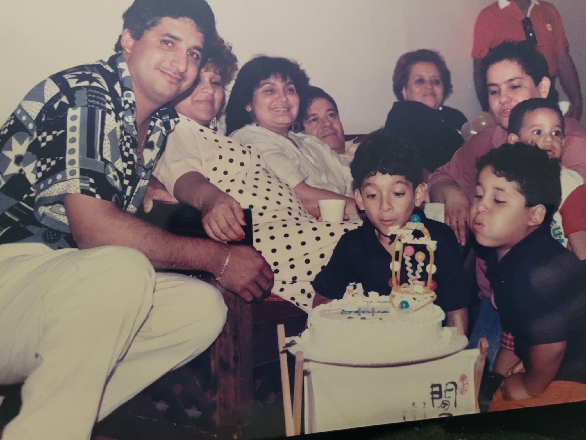 Kids blow out candles on a colorful cake with family and friends in a festive setting.