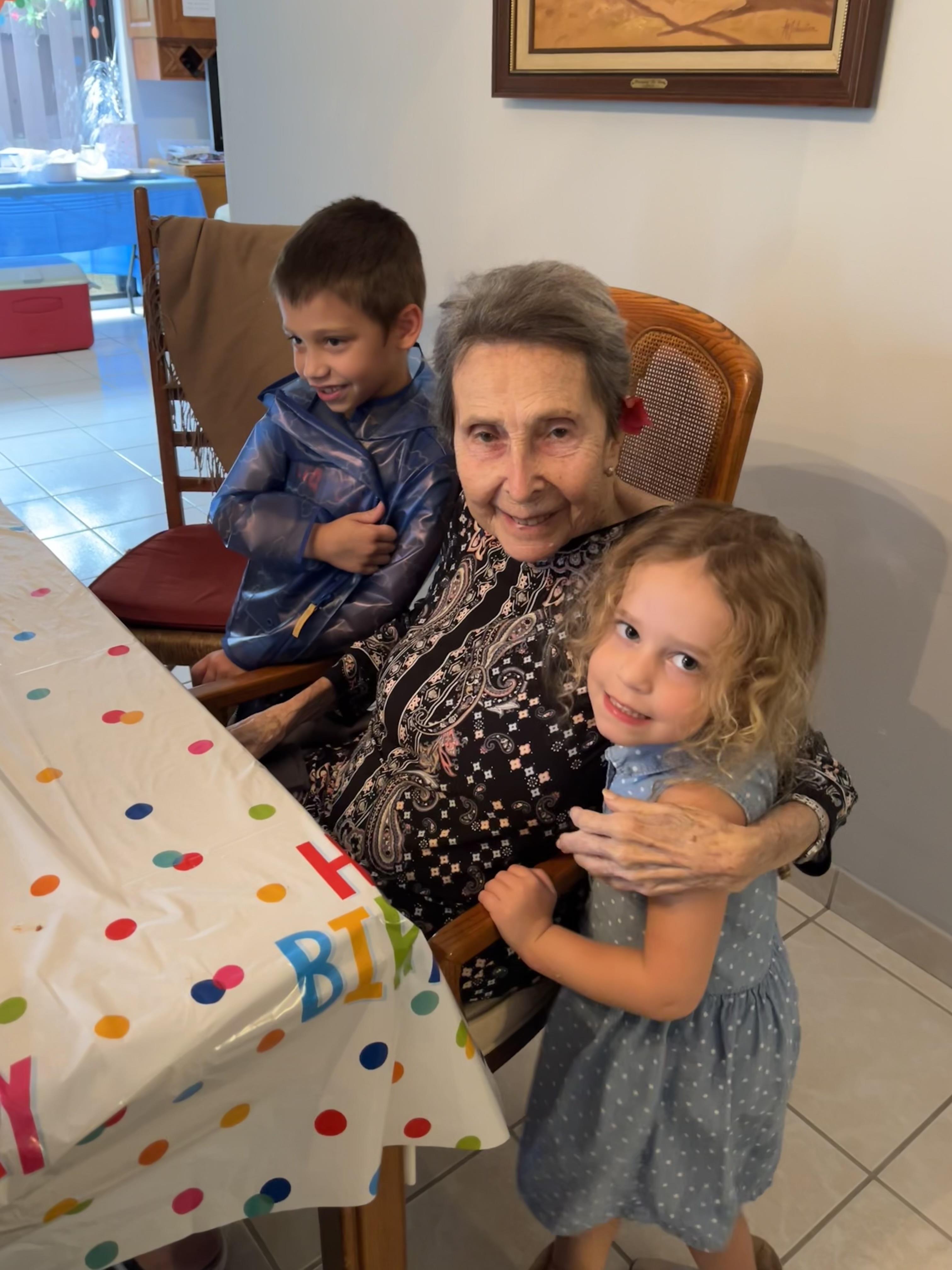 Children gather around a joyful elder at a birthday celebration, smiles and love filling the air.