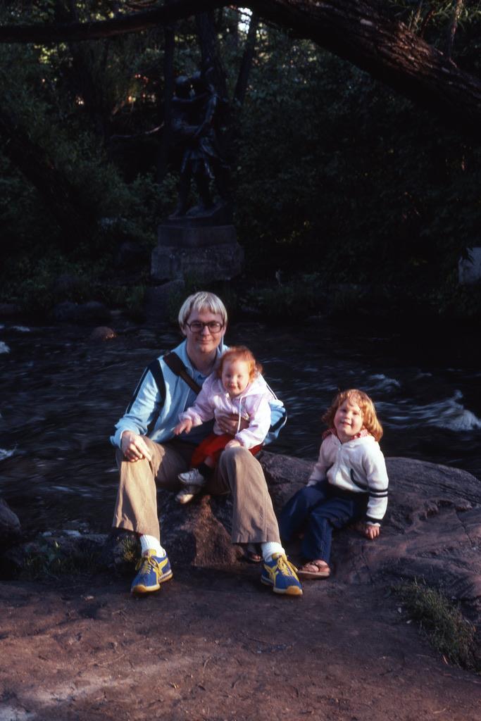 A man and two children sitting on a rock