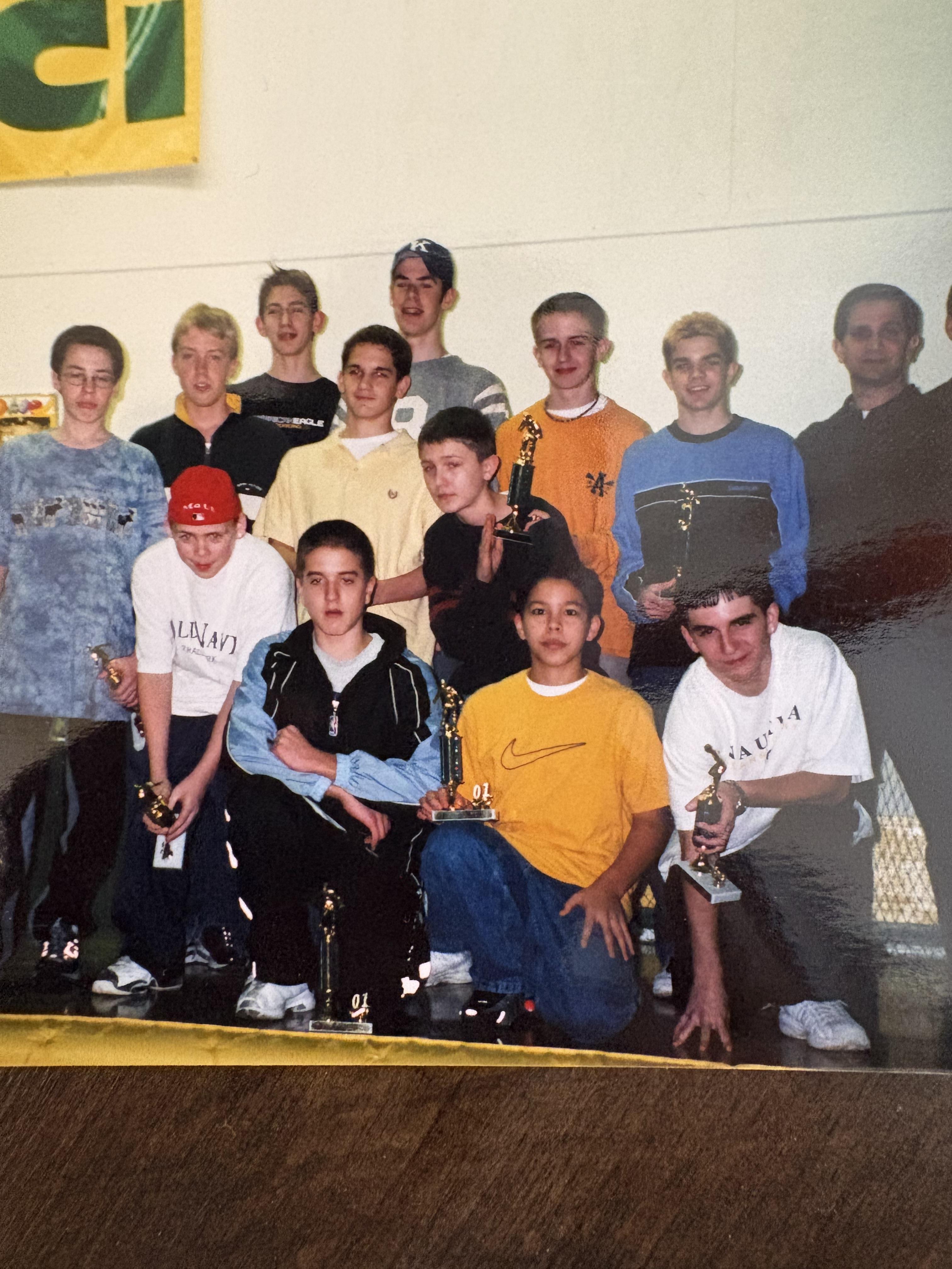 Young athletes pose happily with their trophies in a gym, showcasing their achievements.
