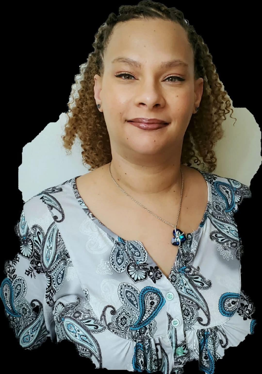 A woman with long curls and a patterned blouse smiles, highlighting her accessory in bright light.