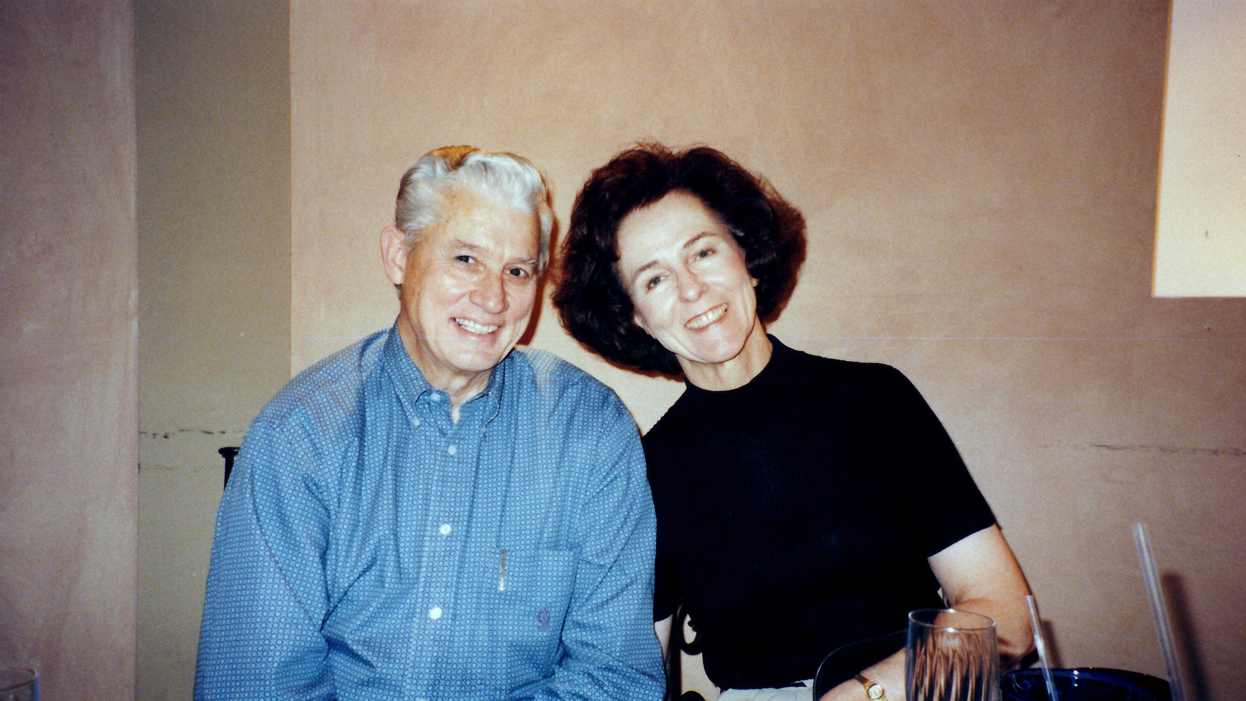 An elderly couple smiles warmly as they enjoy each other's company at a cozy restaurant.