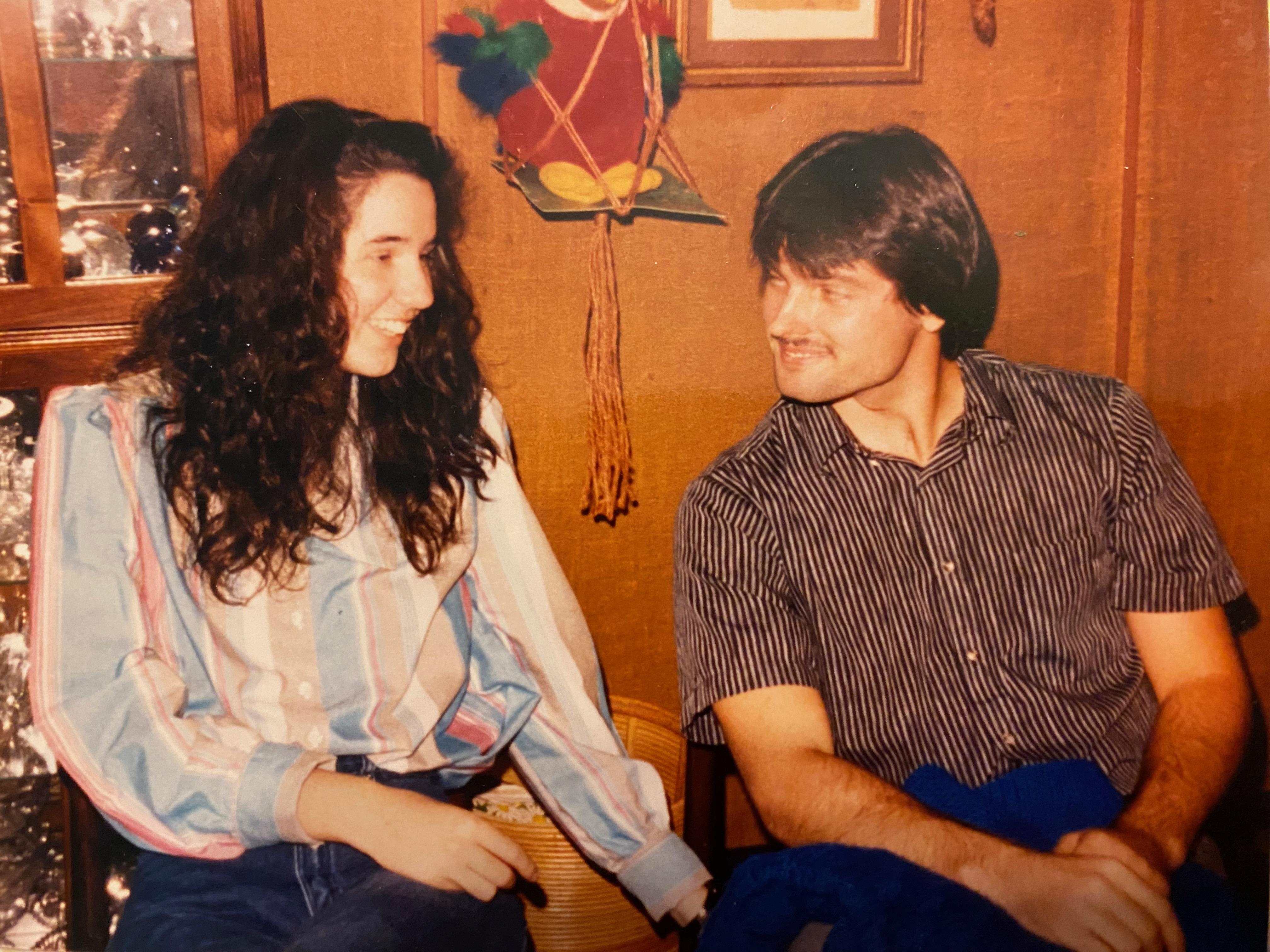 A man and woman share laughter and a joyful moment in a warmly lit room filled with decorations.