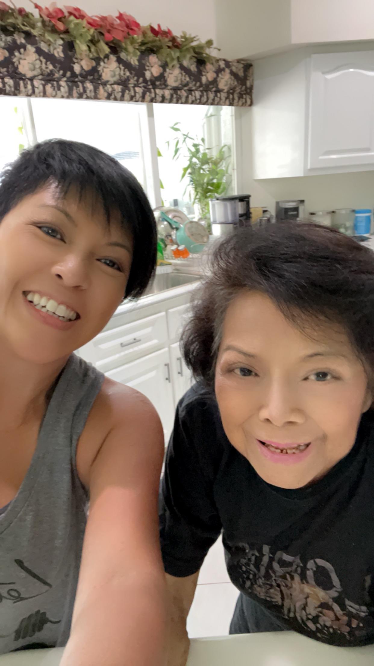 Two women smiling happily while spending time together in a bright kitchen, showcasing a warm bond.