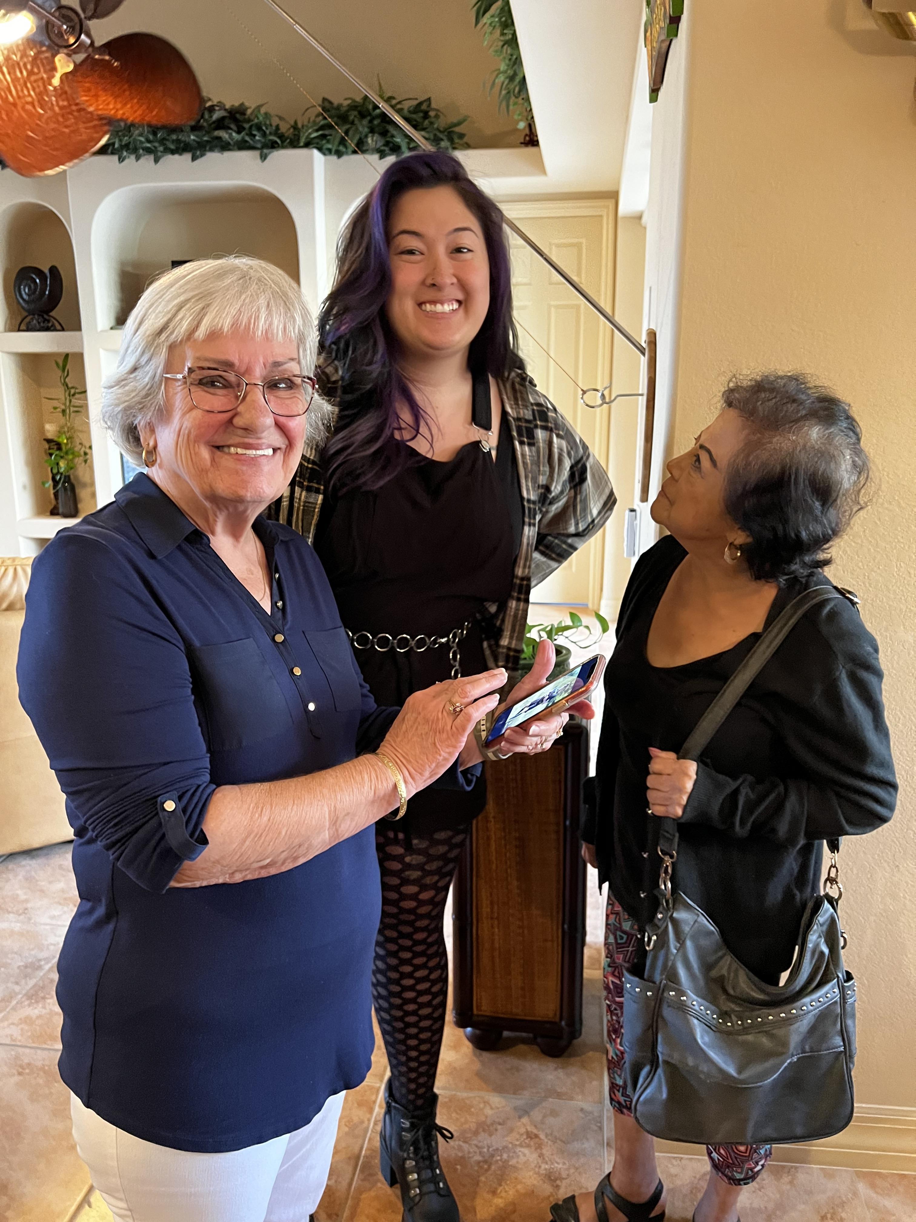 Women of different ages engage in conversation while holding gifts in a warm home setting.