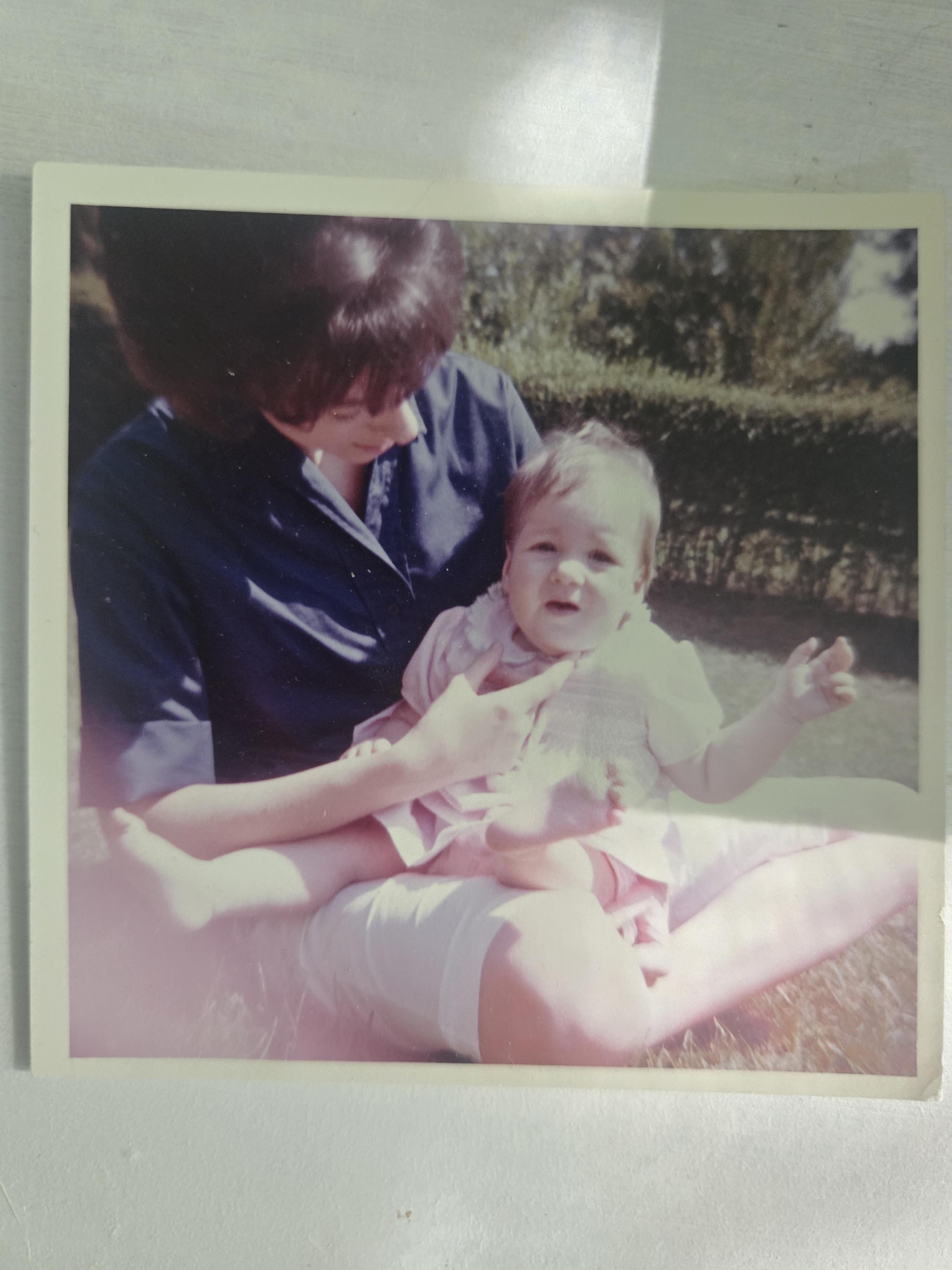 A parent enjoys quality time with their child in a garden, surrounded by greenery and sunshine.