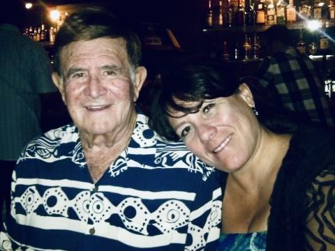 A man and woman share a warm smile while dining in a bustling restaurant during the evening.