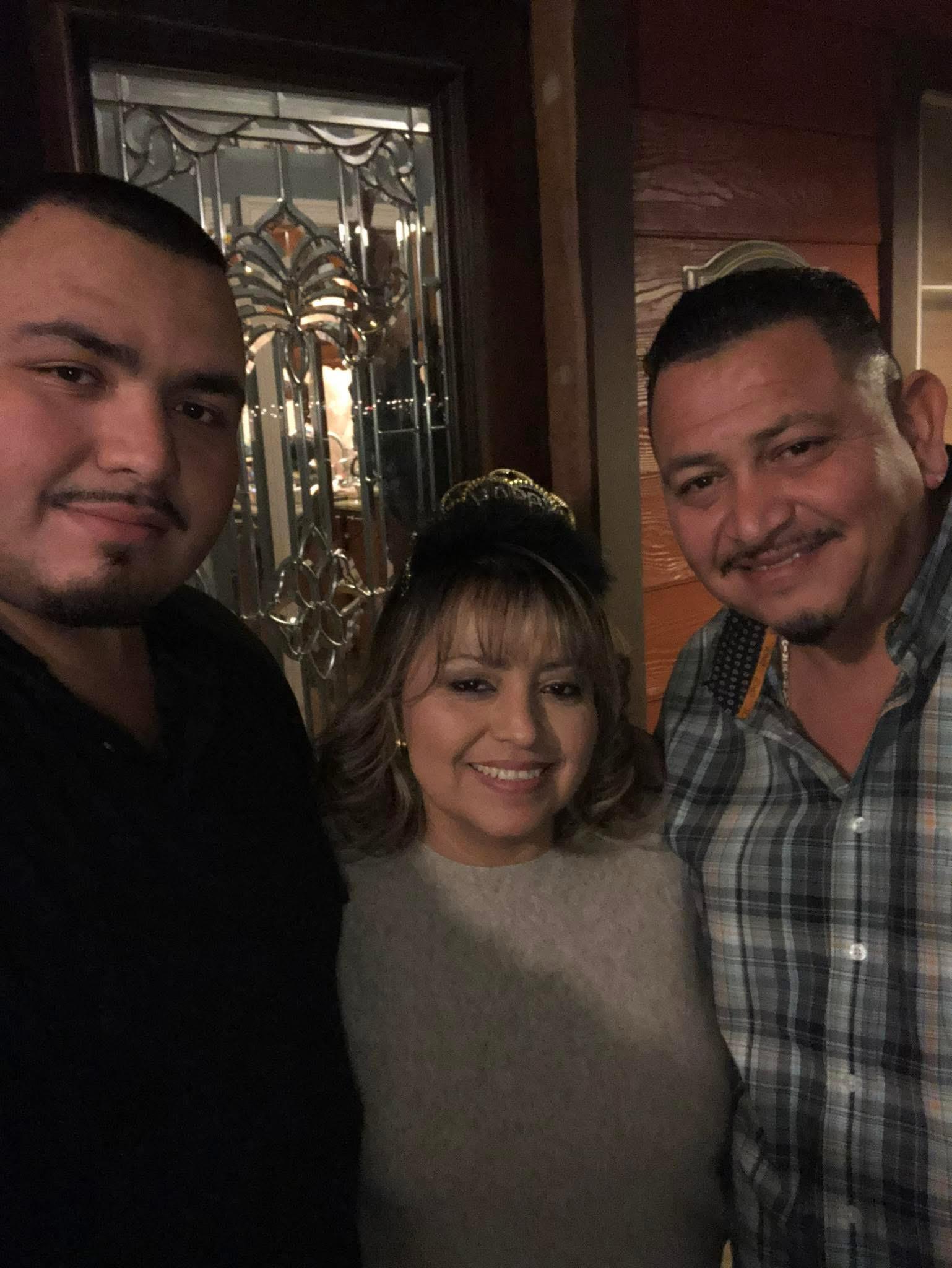 Three friends are smiling together in a cozy setting during a lively evening celebration.
