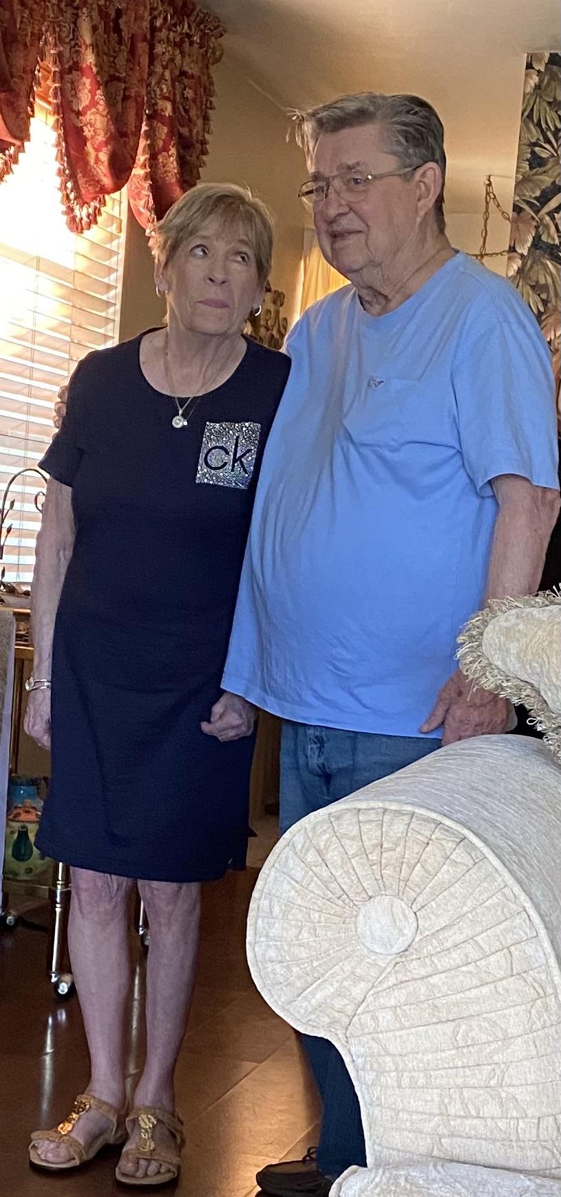 Elderly couple holds hands while enjoying a family gathering in their comfortable home.