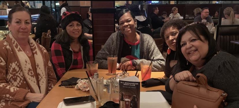 Five friends are gathered around a table at a lively restaurant, enjoying dinner together.