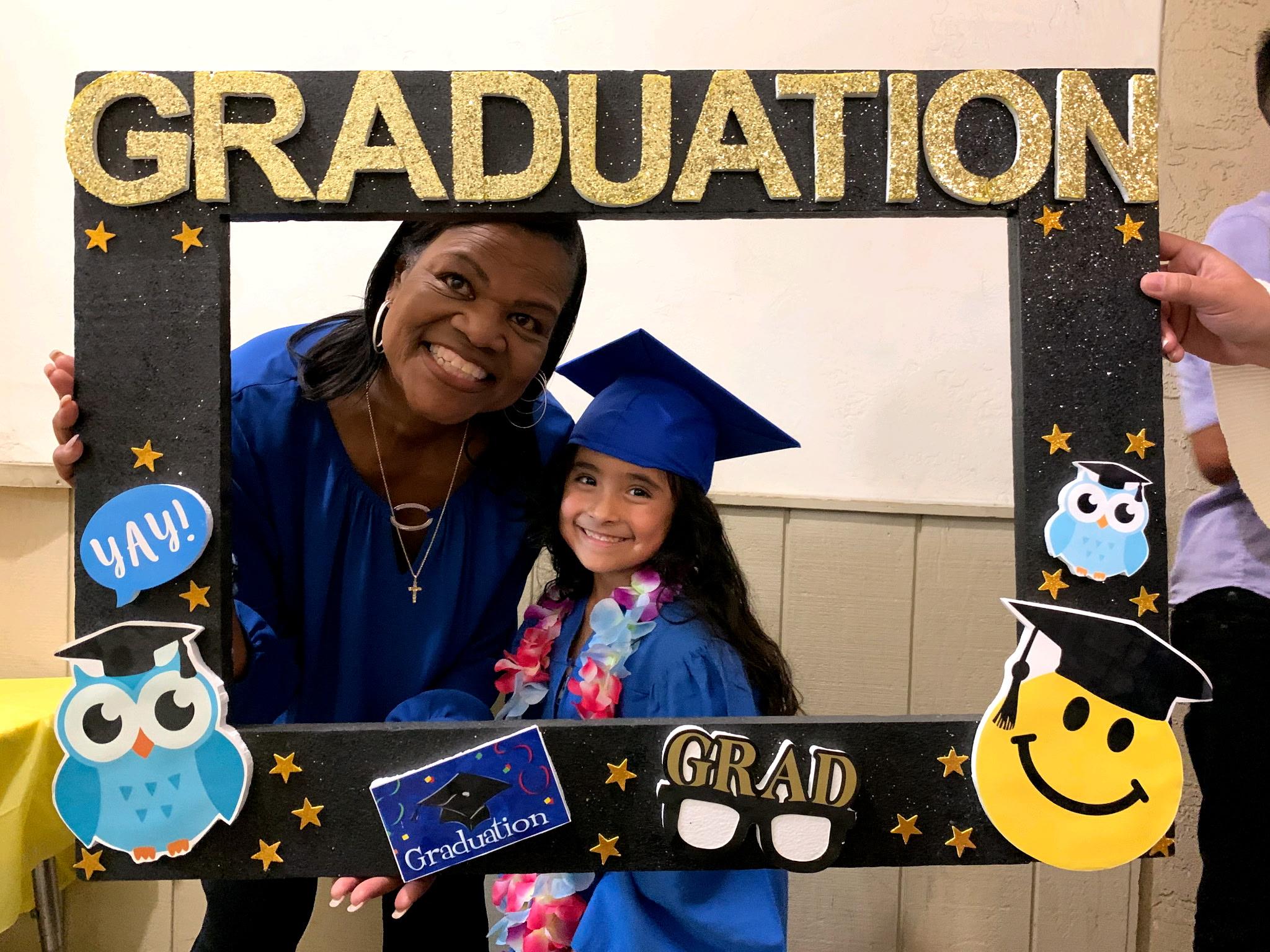 A joyful graduation moment with a girl and her proud family member celebrating.