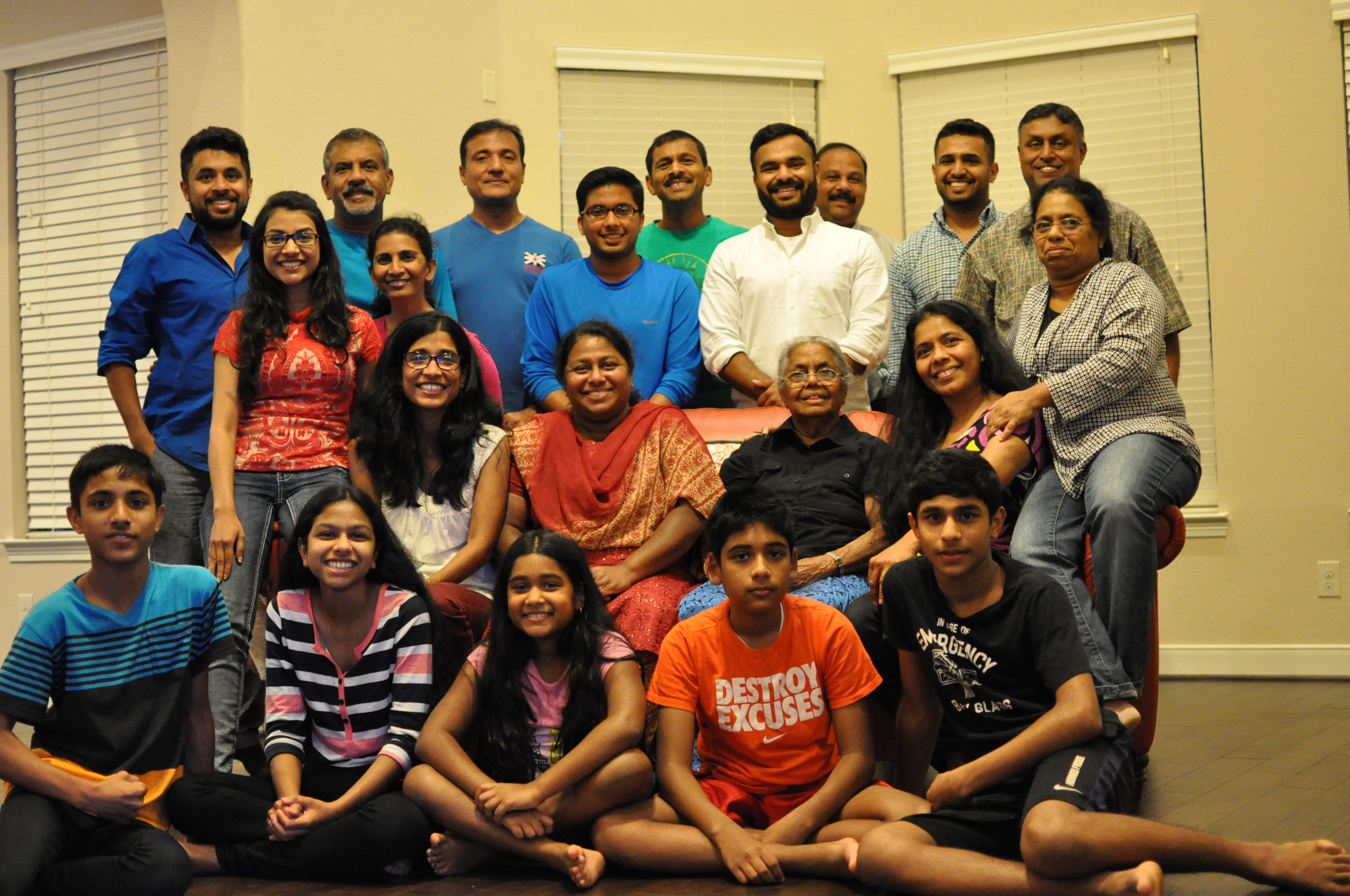 Group of family members posing together in a cozy living room setting, smiling joyfully.