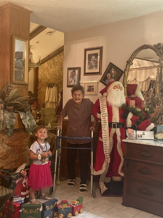 A woman standing with a walker and a child in a room with santa claus