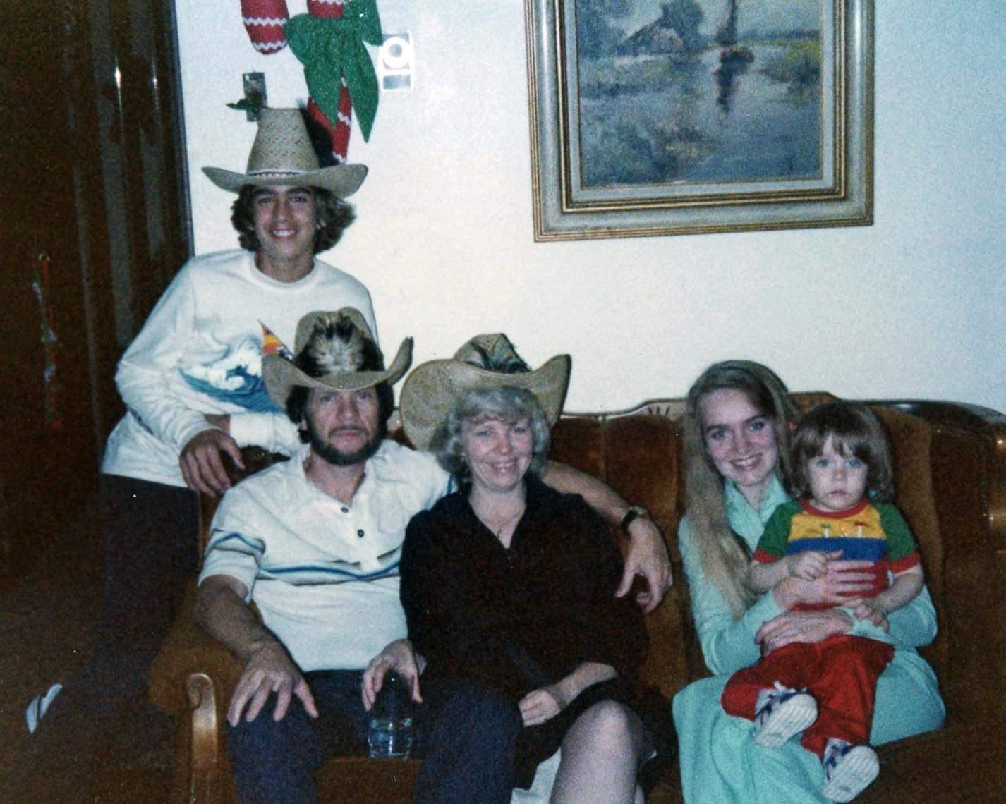 A group of five family members dressed in cowboy hats enjoys a cheerful moment together.