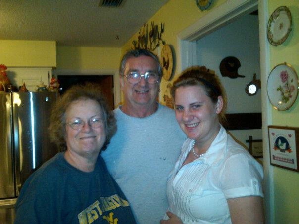 Three family members smile warmly together in a well-decorated kitchen during a joyful gathering.