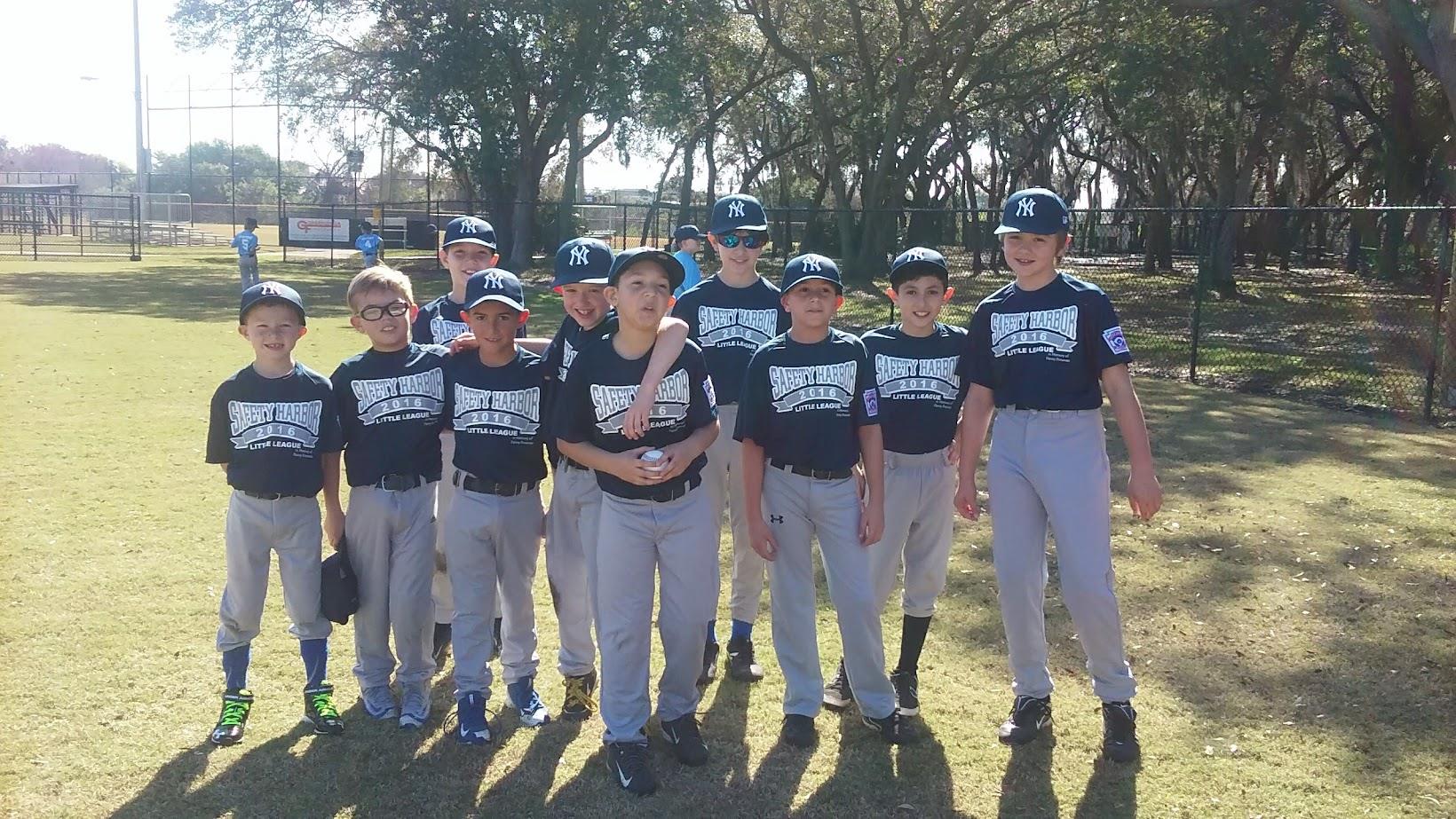Group of young baseball players stands together in matching uniforms at the park, enjoying practice.