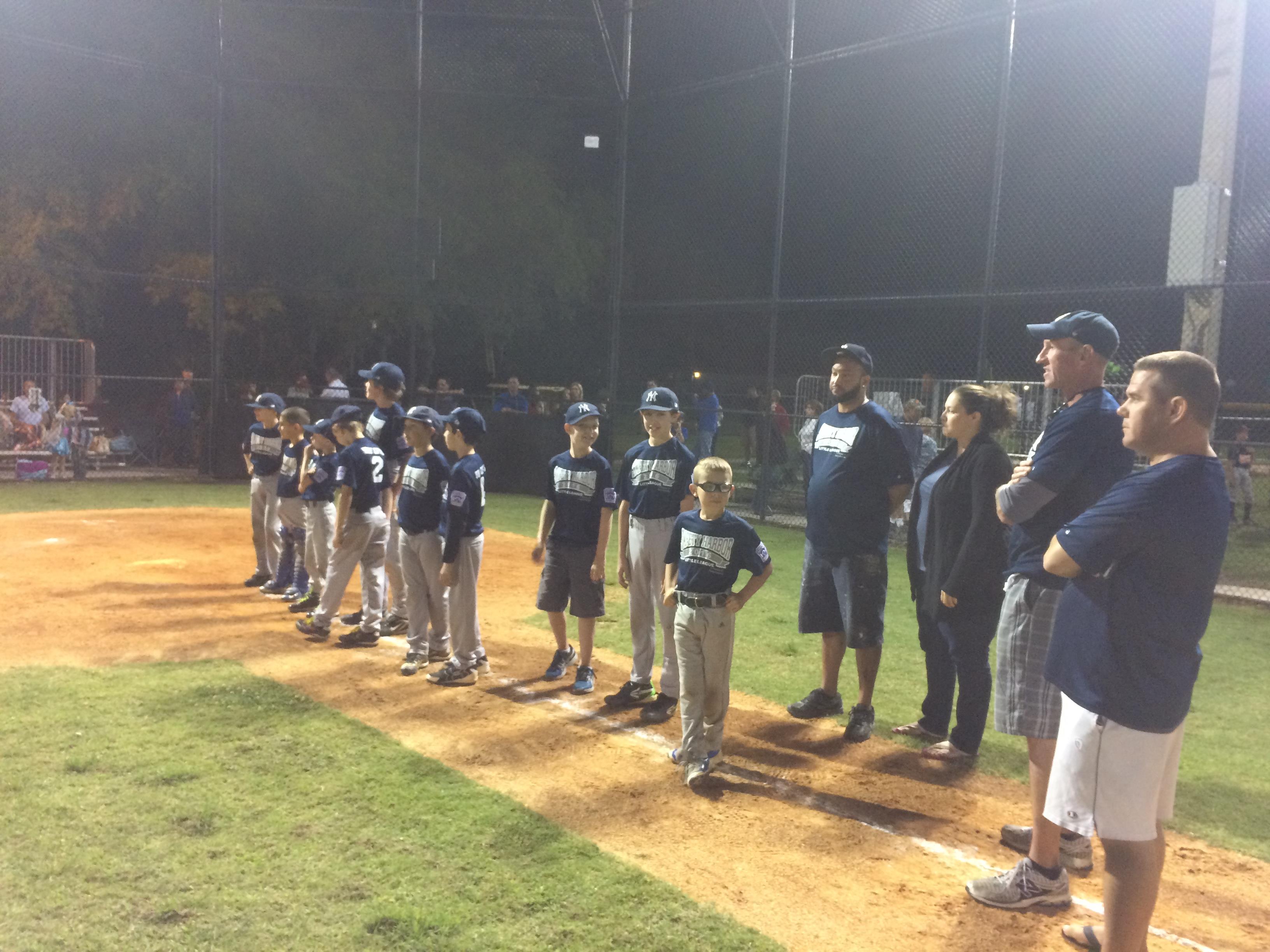 Young players, coaches, and parents gather under bright lights for team recognition.