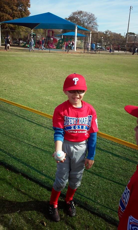 Young athlete holds a baseball with confidence during a practice session at the park.